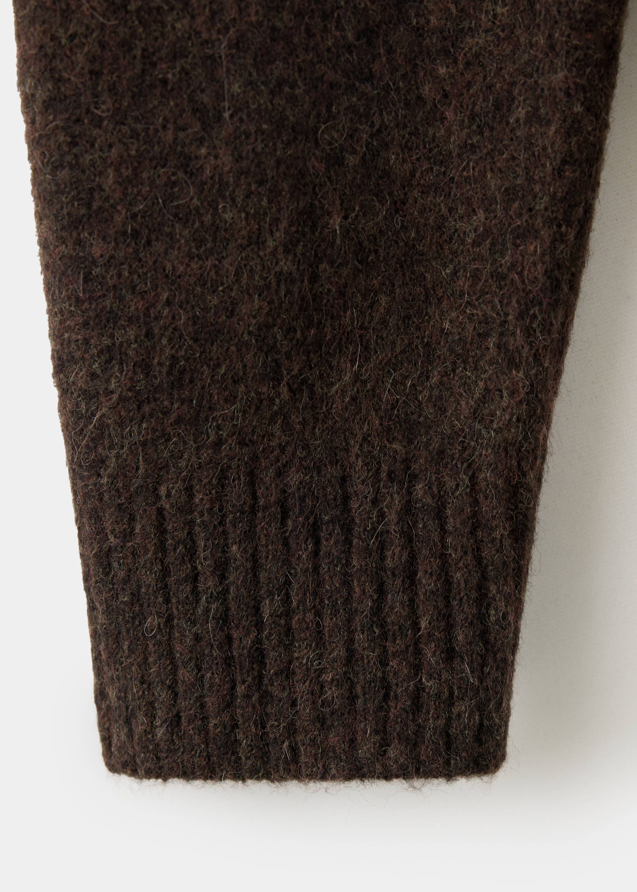 Close-up of the fuzzy texture and ribbed cuff of a dark brown cardigan.