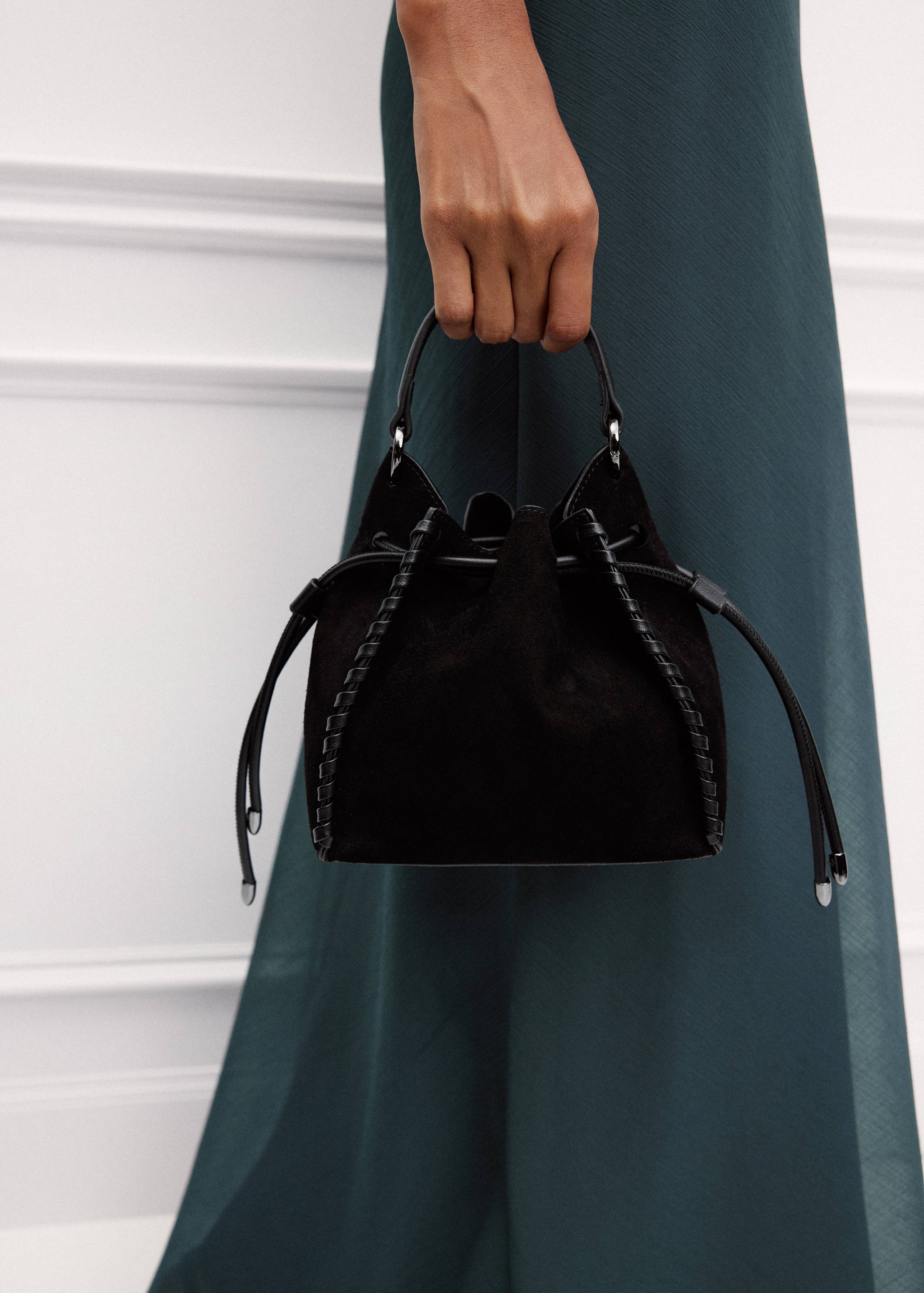 Black suede mini bucket bag with a top handle and drawstring closure.