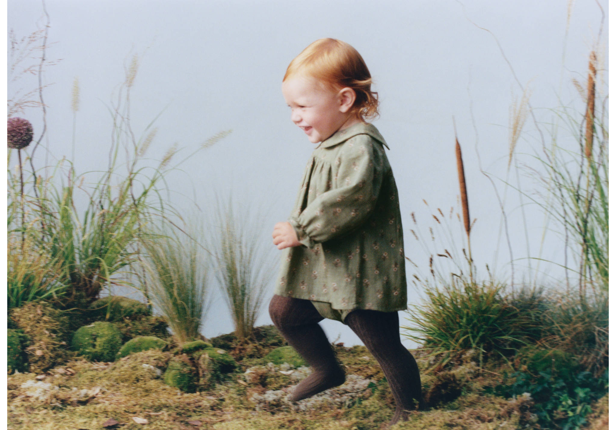 Green floral dress with rounded collar and long sleeves worn by a toddler.