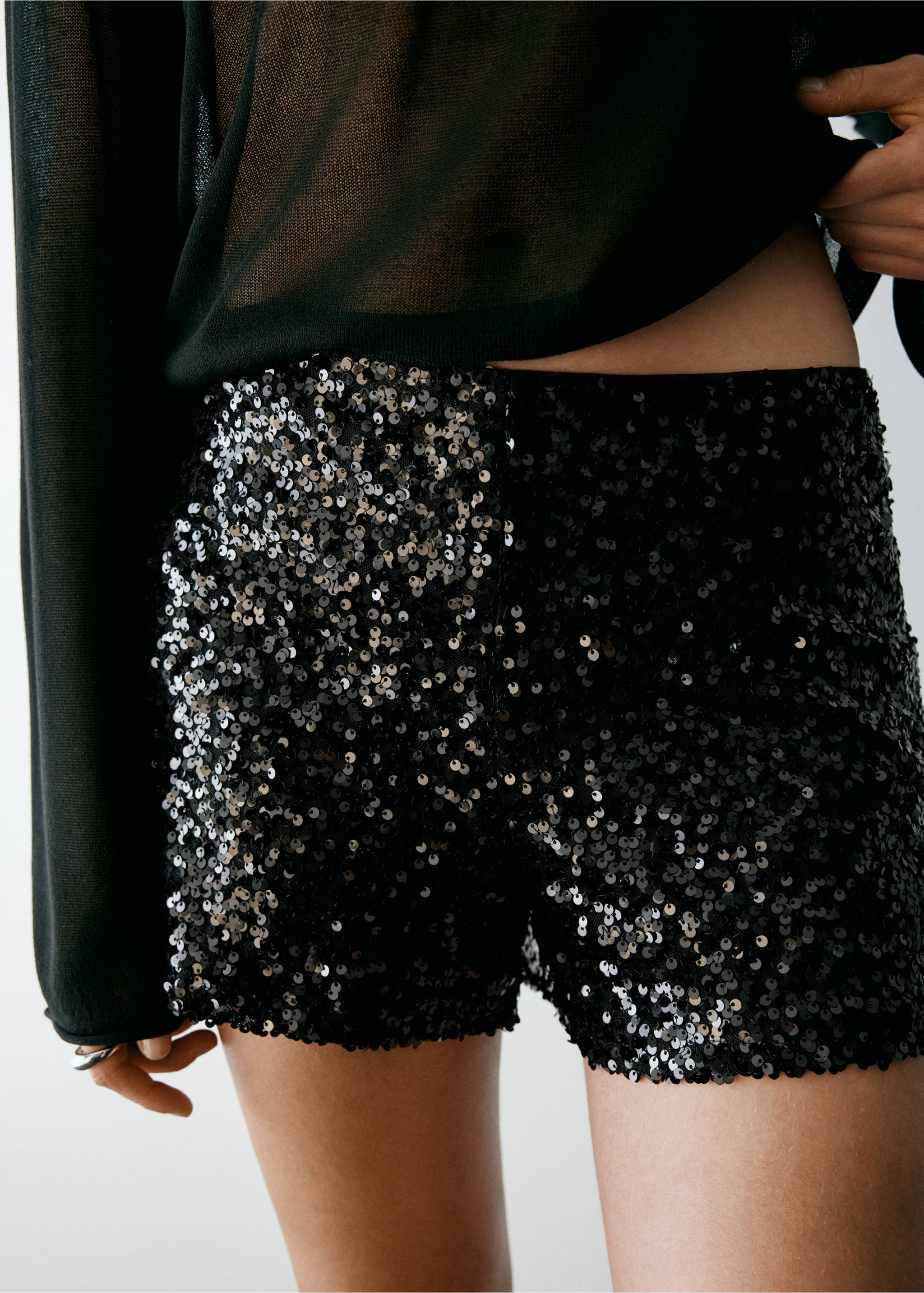 Black sequin shorts paired with a sheer black top., Black. Ref: 37077929-00.