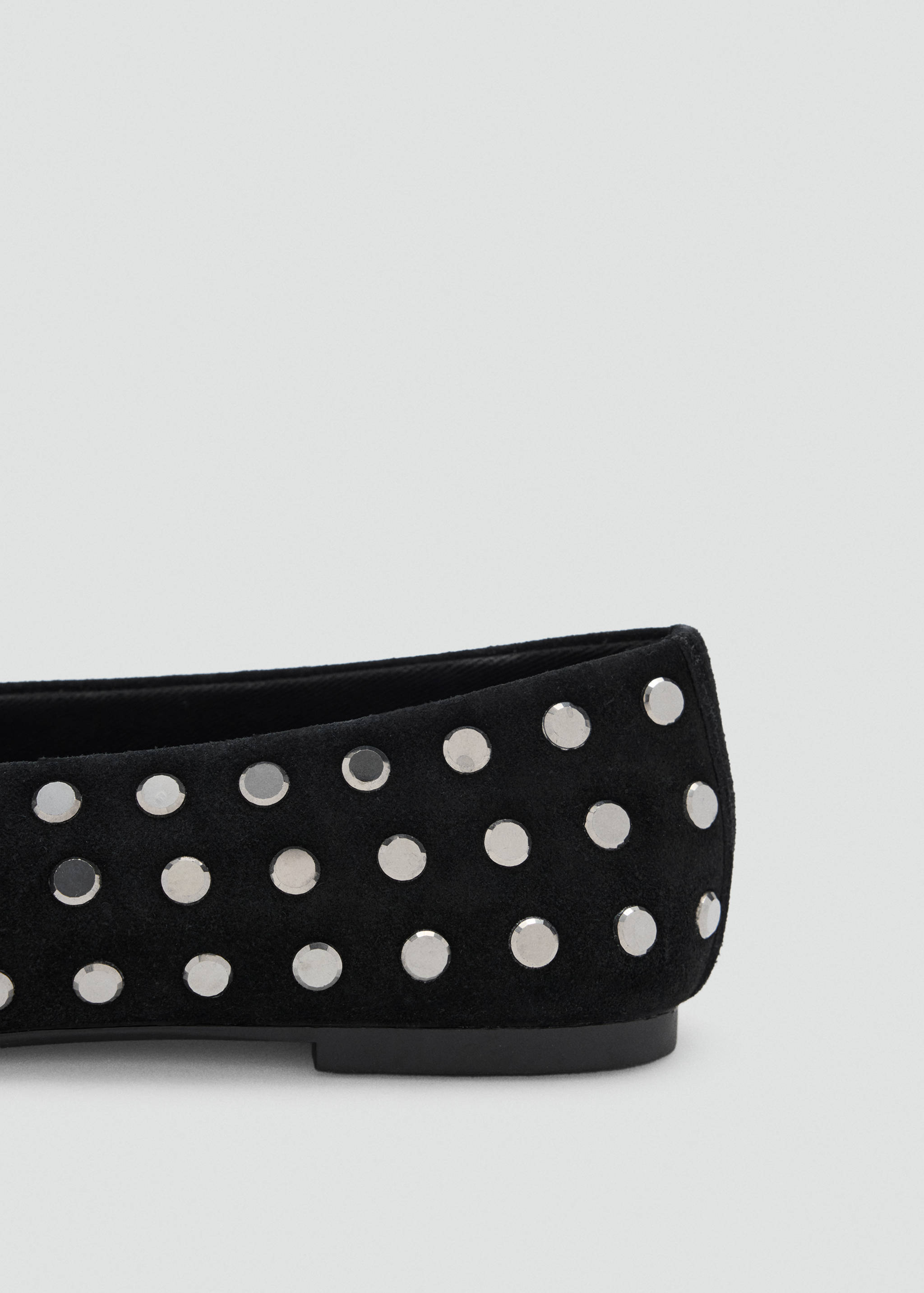Close-up of black shoes with silver-toned metal studs.