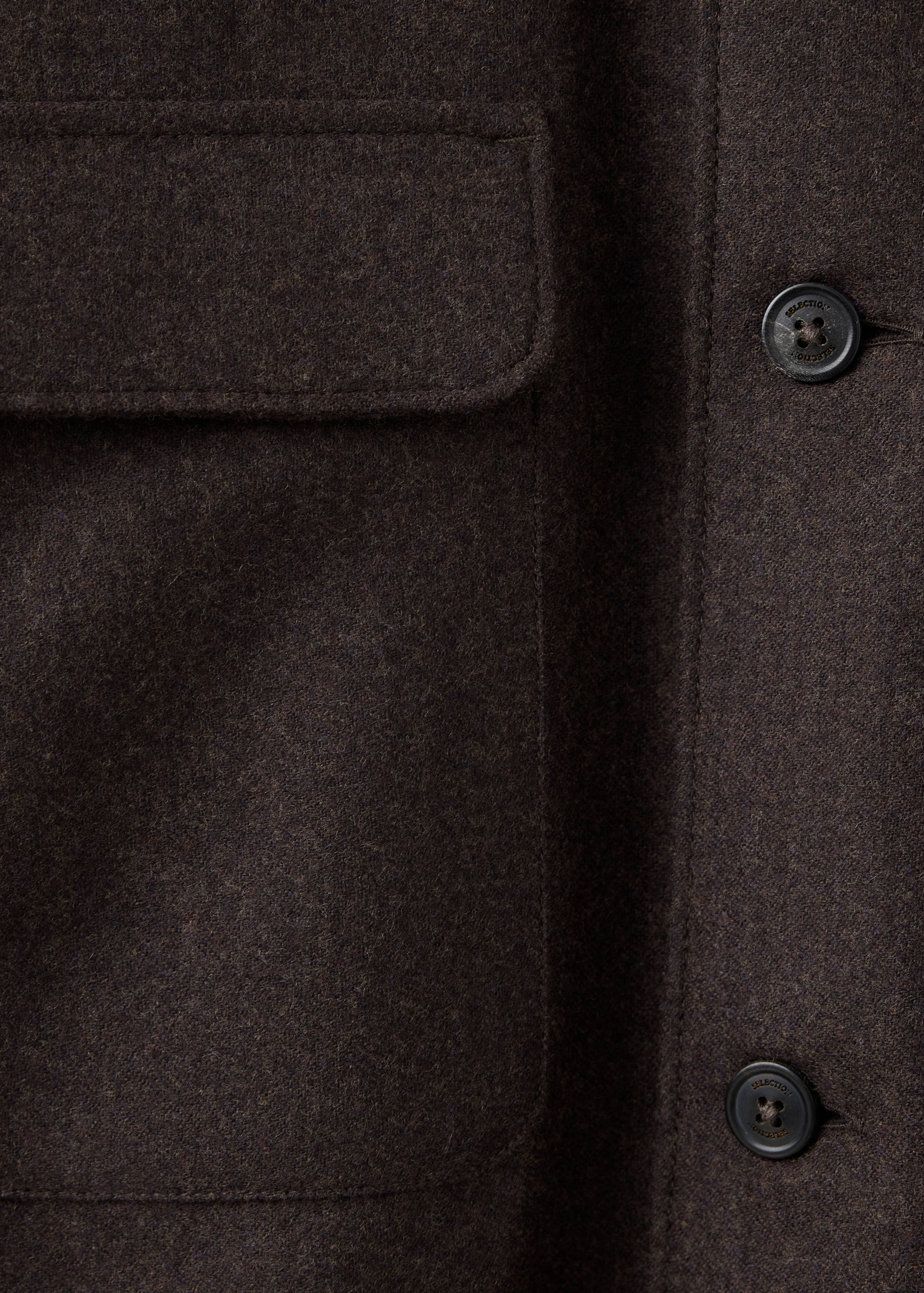 Close-up of a dark brown overshirt fabric and pocket detail.