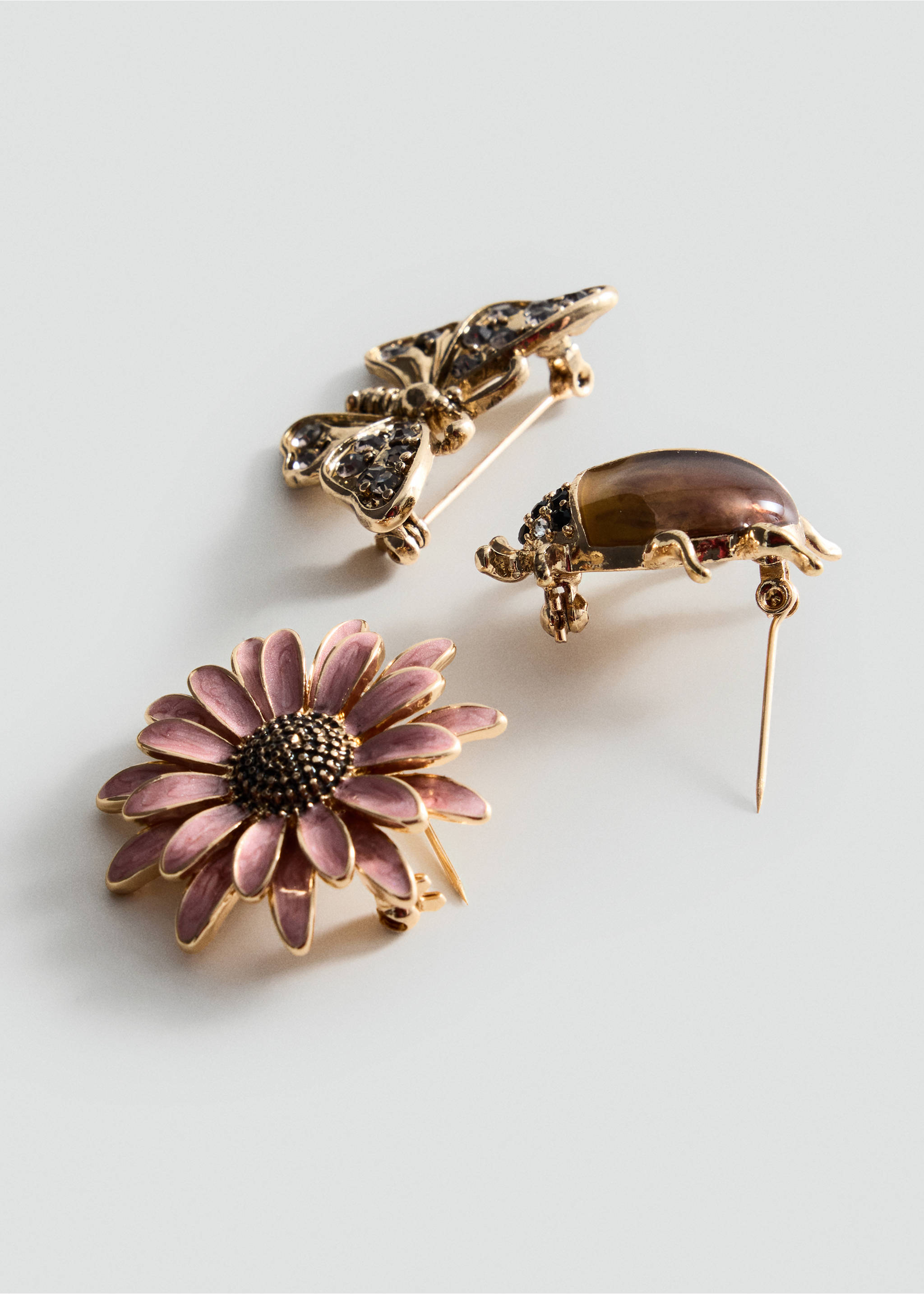 Three decorative gold-tone brooches including a pink flower, a crystal butterfly, and an amber beetle., Gold. Ref: 37077944-00.