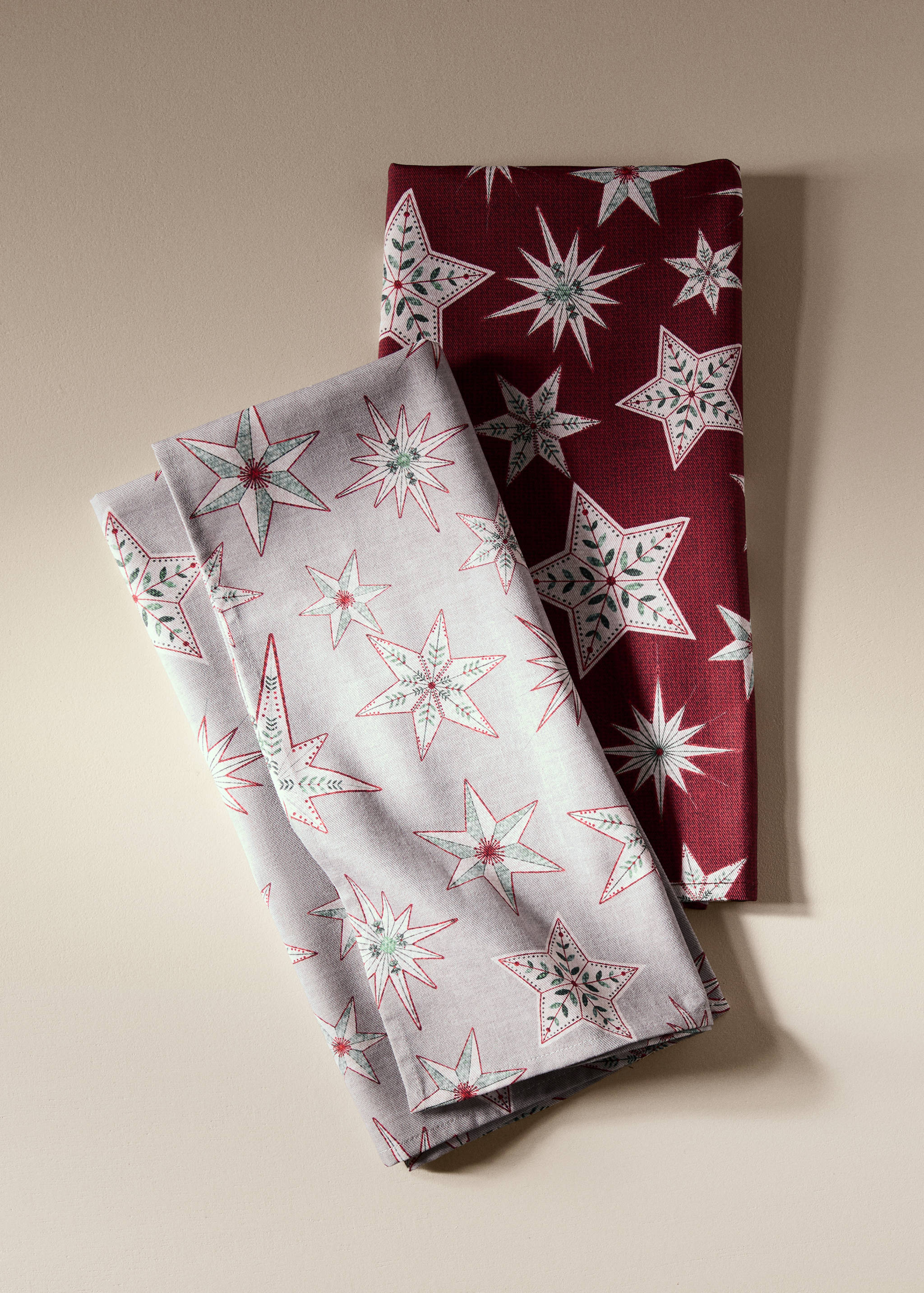 Two folded kitchen towels with a festive star pattern in red and grey.