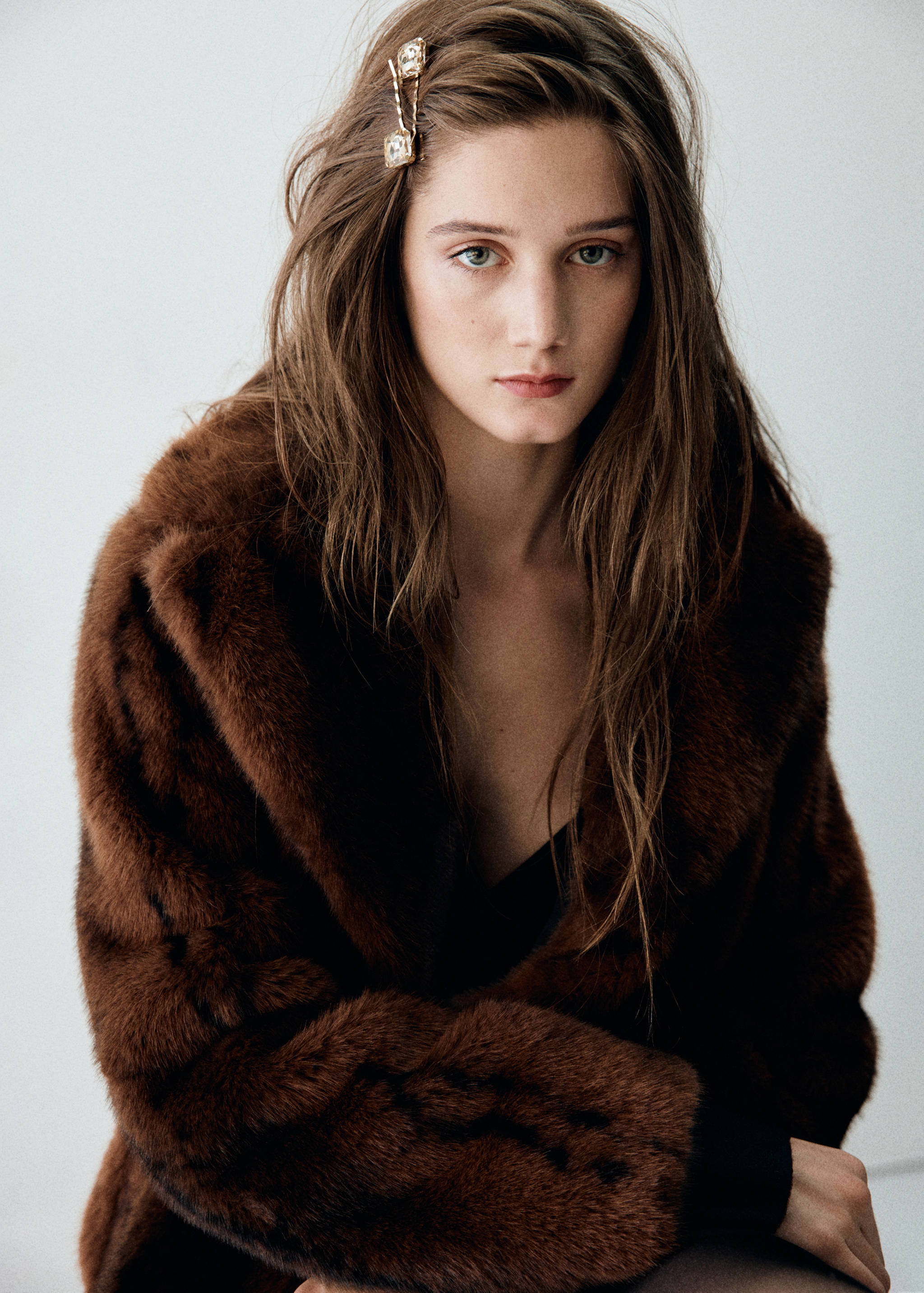Hair accessory with jewelled embellishments worn by a model in a brown faux-fur coat.