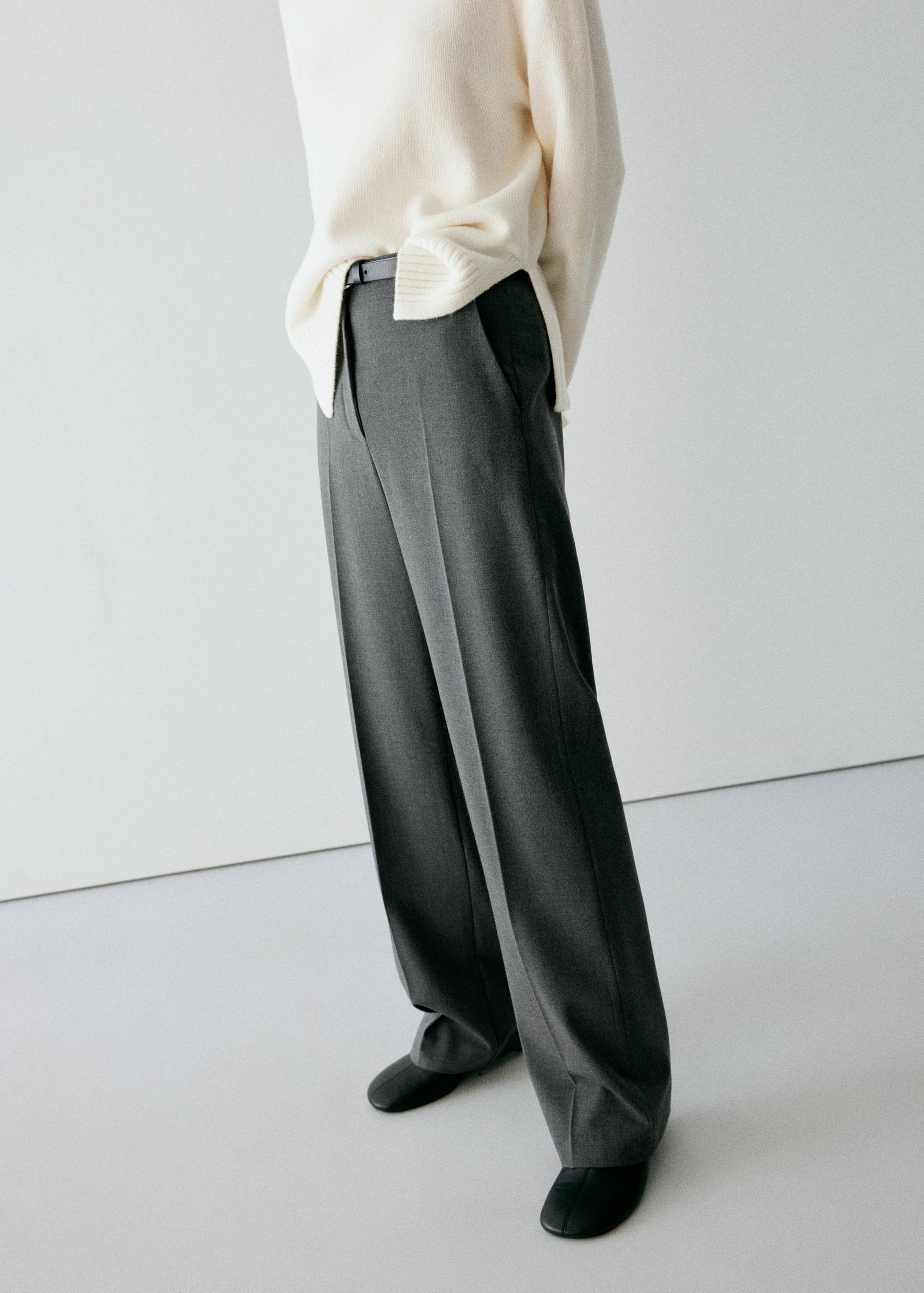 Dark grey straight trousers with pressed creases, styled with a cream knit sweater.