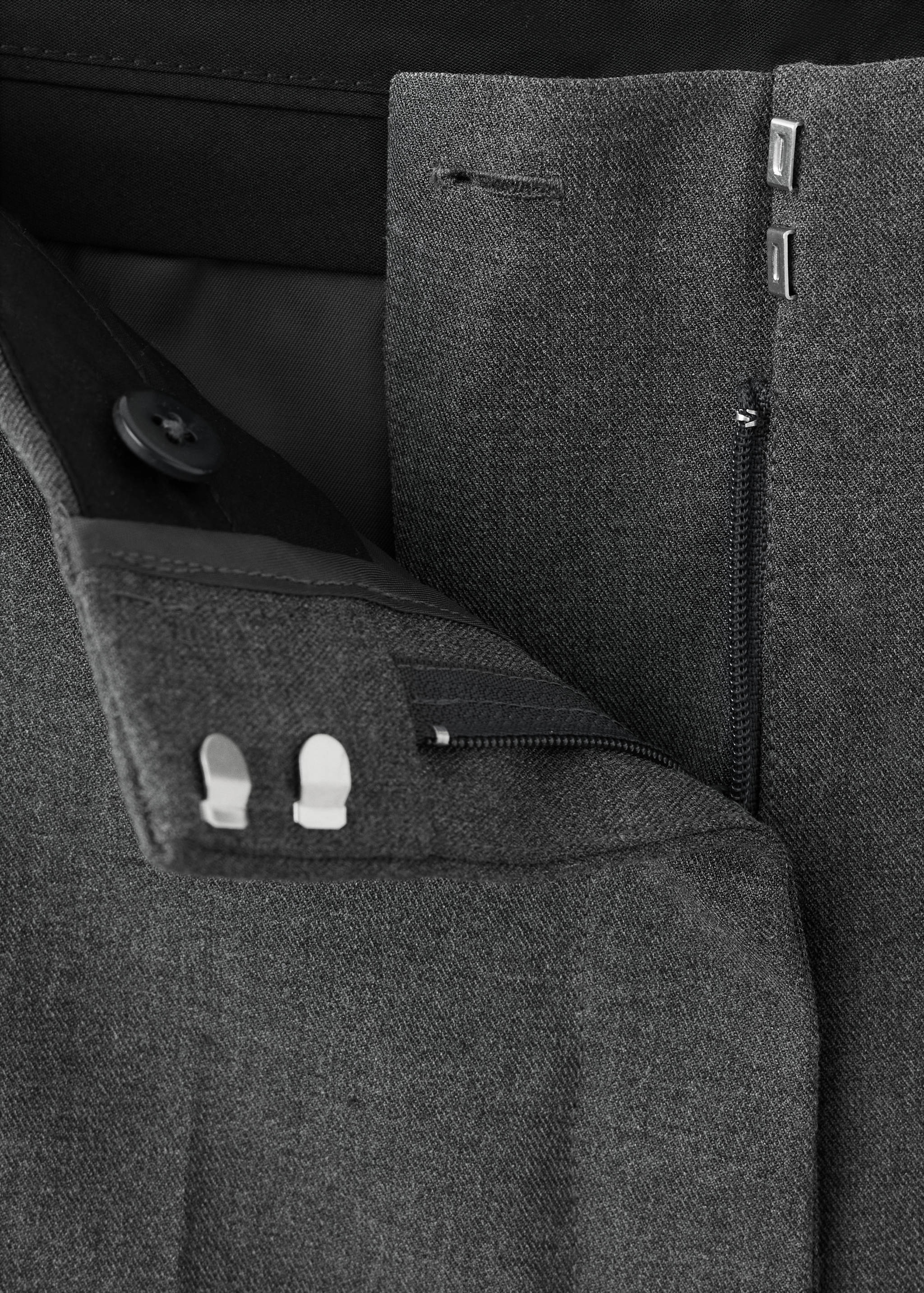 Close-up of dark grey trousers focusing on the waistband and fastening details.
