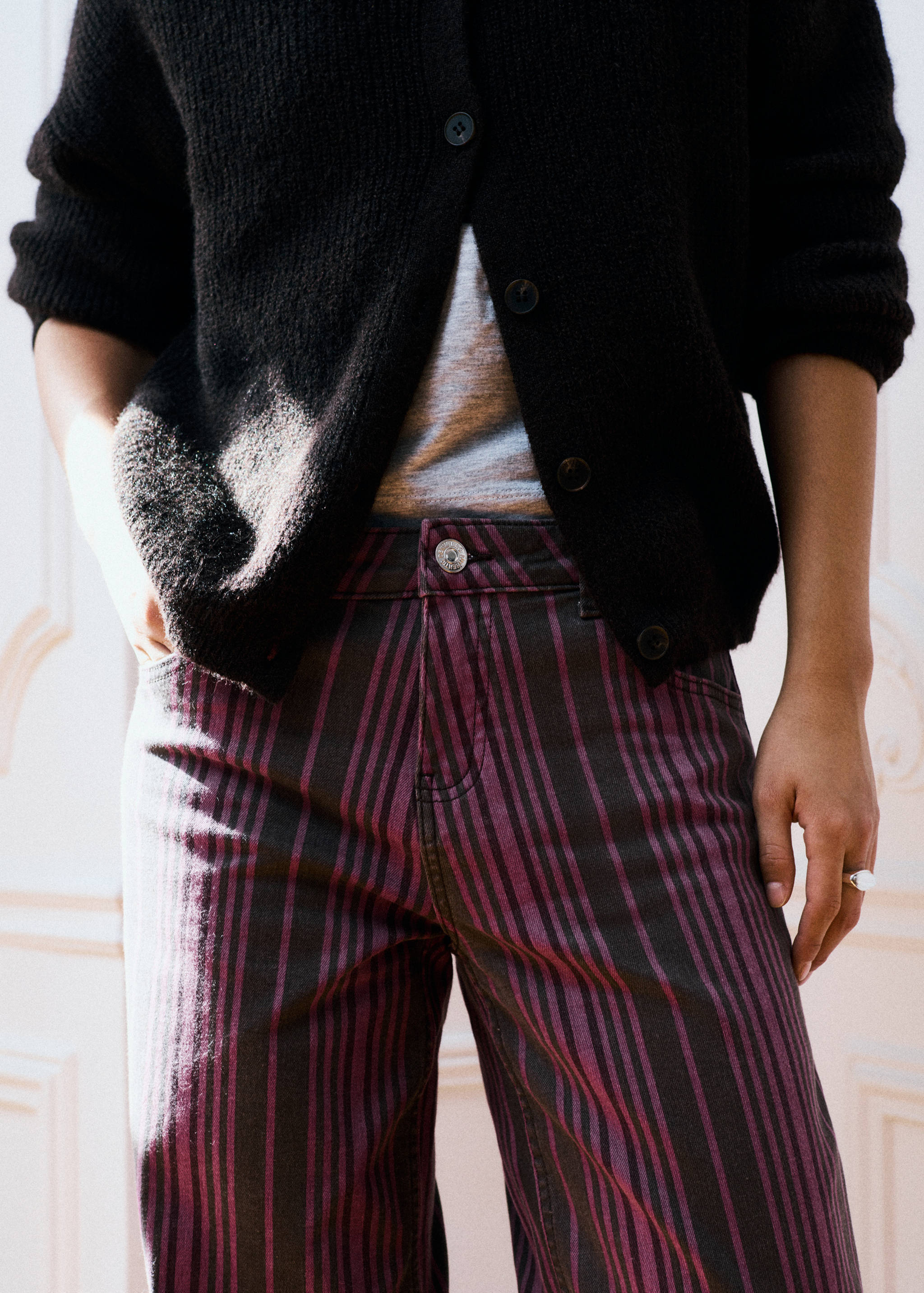 Pantalones de rayas en morado oscuro y negro combinados con una camiseta gris y un cárdigans negro.