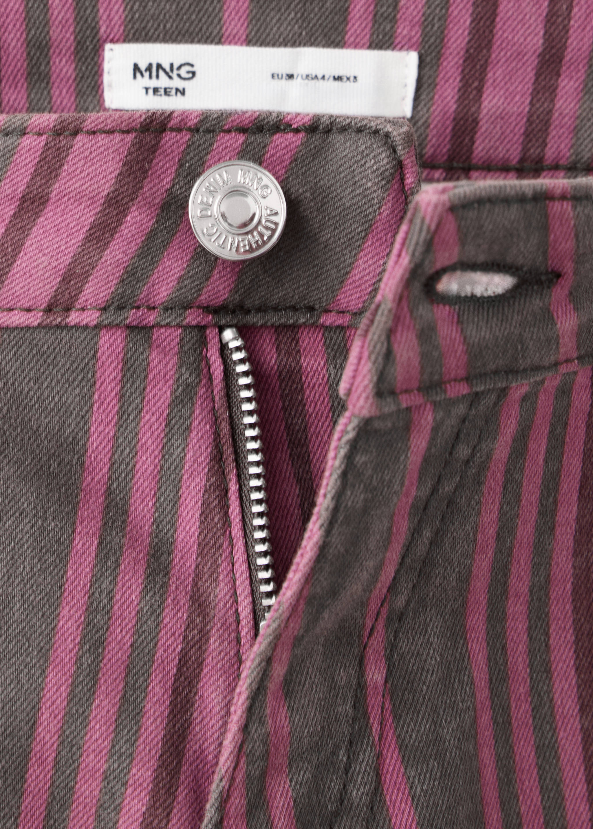 Primer plano de la pretina en pantalones vaqueros de rayas moradas y marrones.