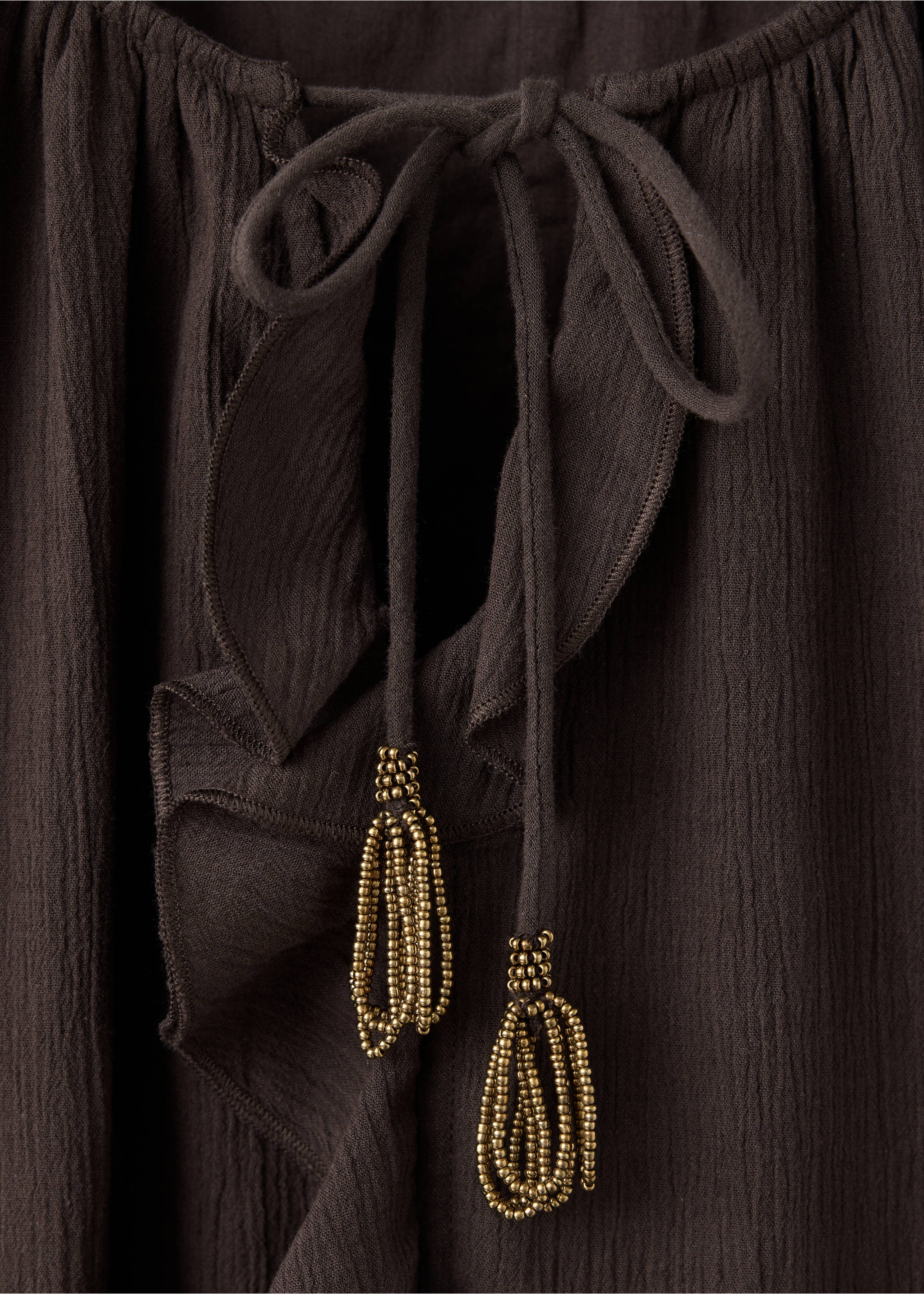 Brown dress detail featuring a ruffled neckline and beaded tassel ties., Brown. Ref: 37078276-00.