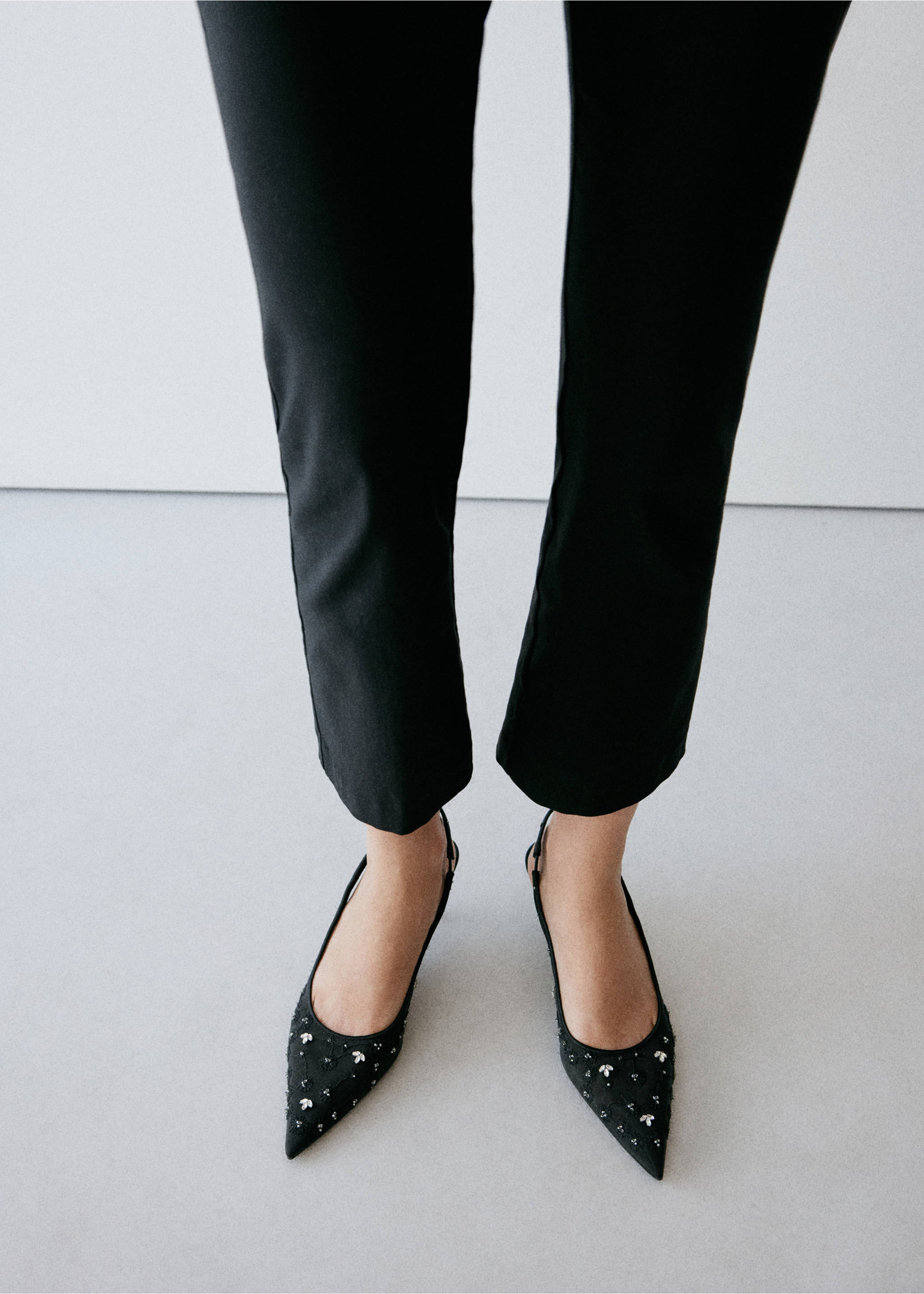 Black pointed-toe slingback shoes with beaded toes worn with trousers., Black. Ref: 37078278-00.
