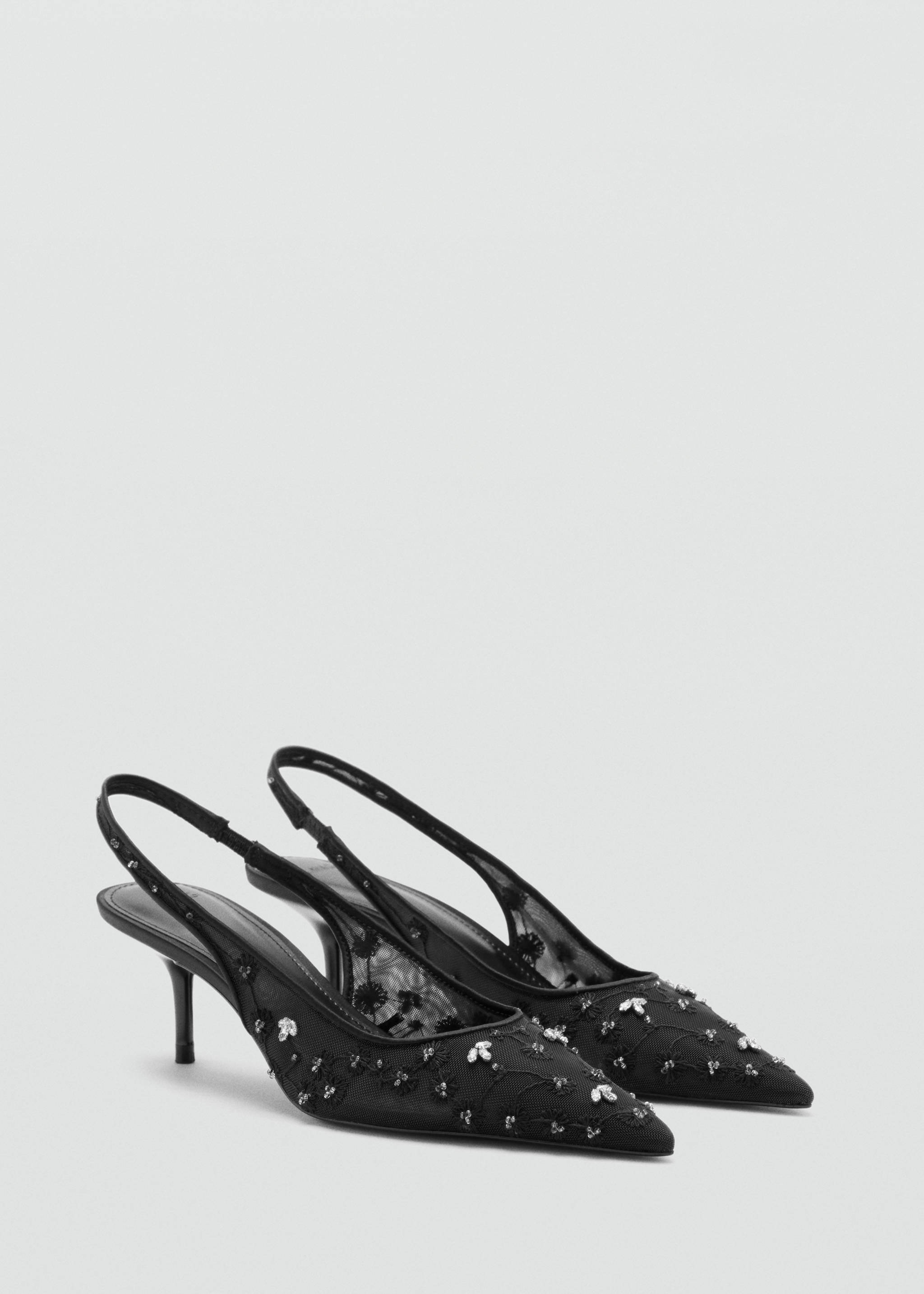 Black slingback shoes with pointed toes, embellished mesh uppers, and stiletto heels.