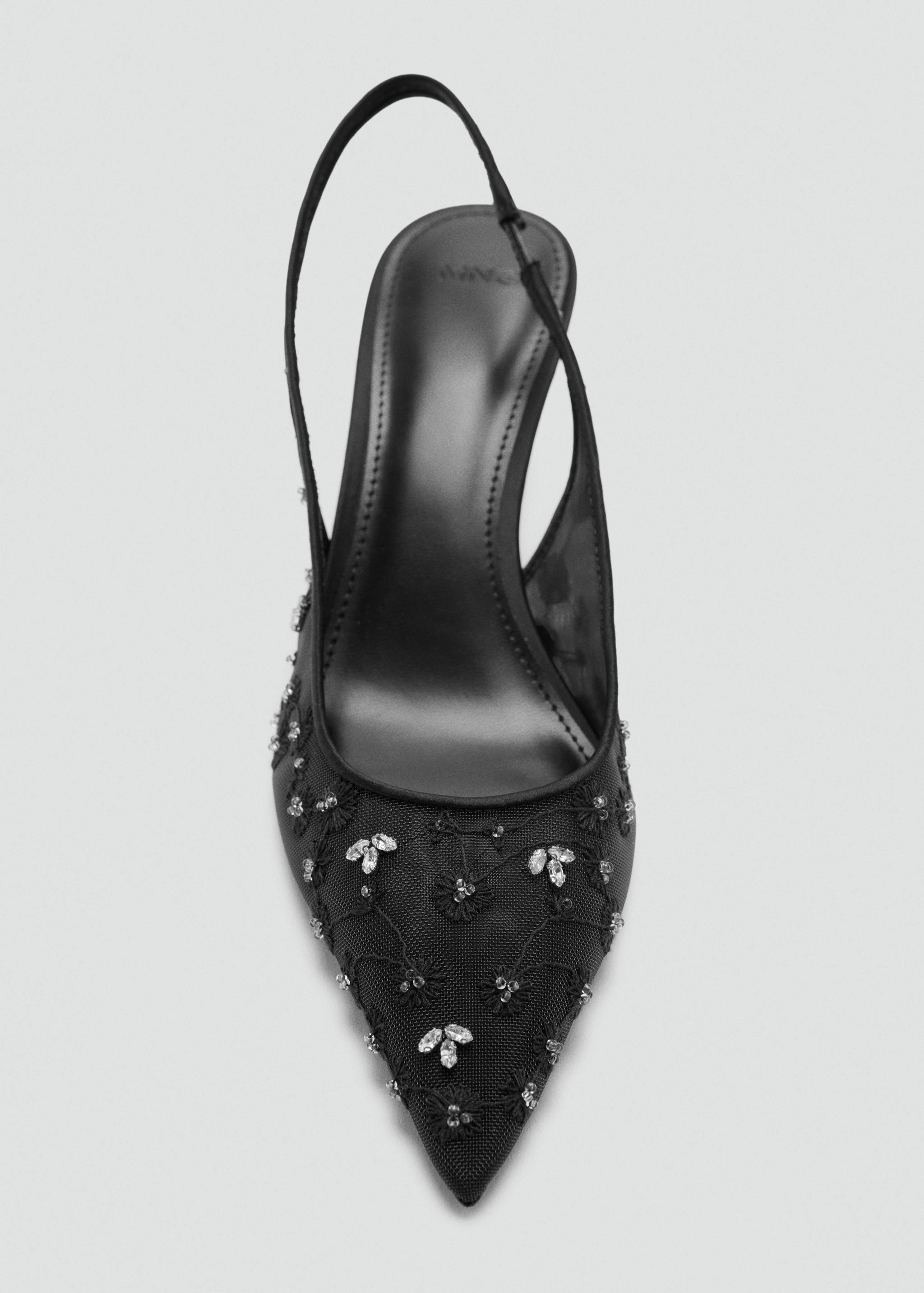Black slingback shoe with pointed toe, sheer mesh upper, embroidery, and crystal embellishments.
