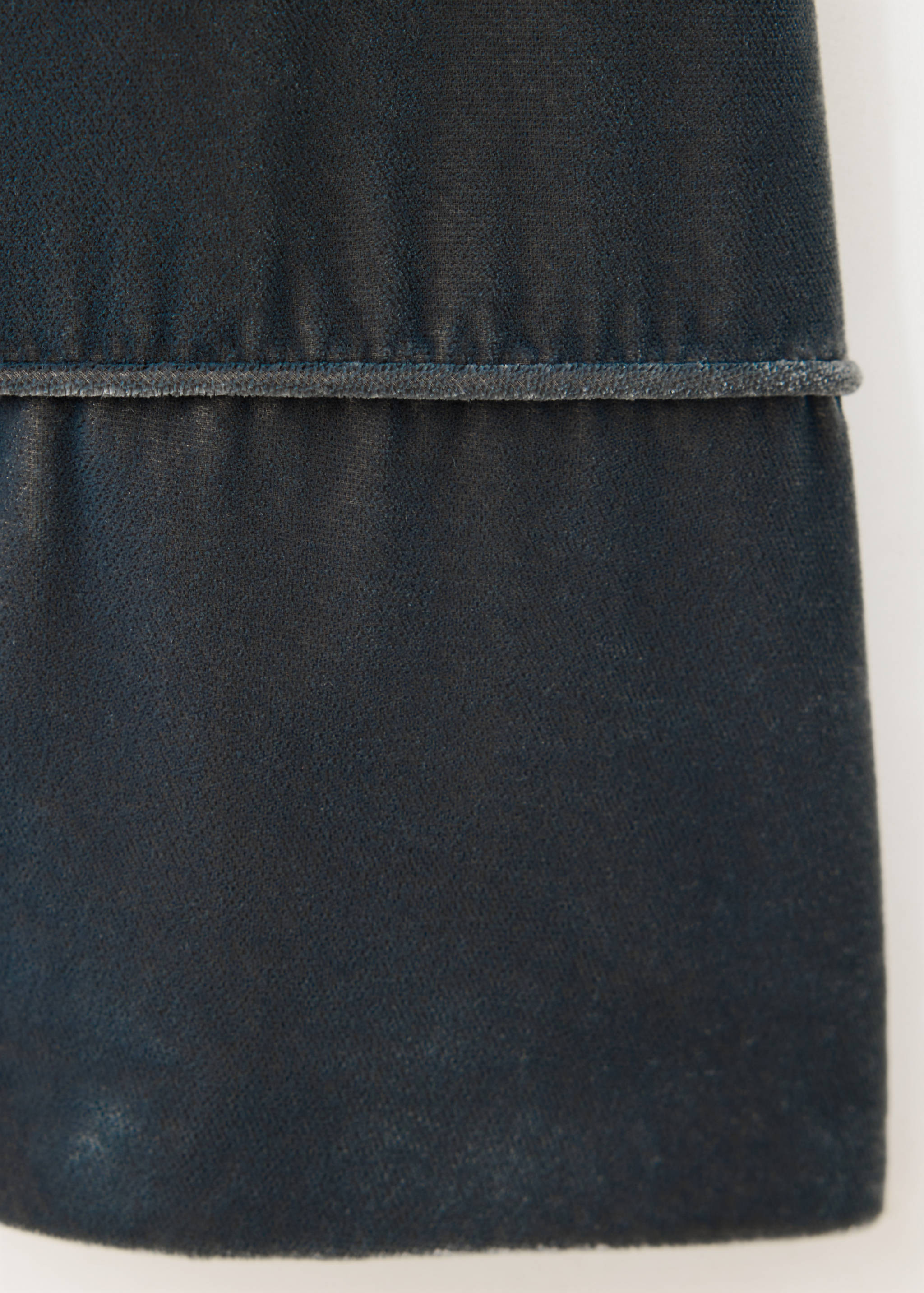Detalle de tejido de una chaqueta azul oscuro que muestra una costura ribeteada.