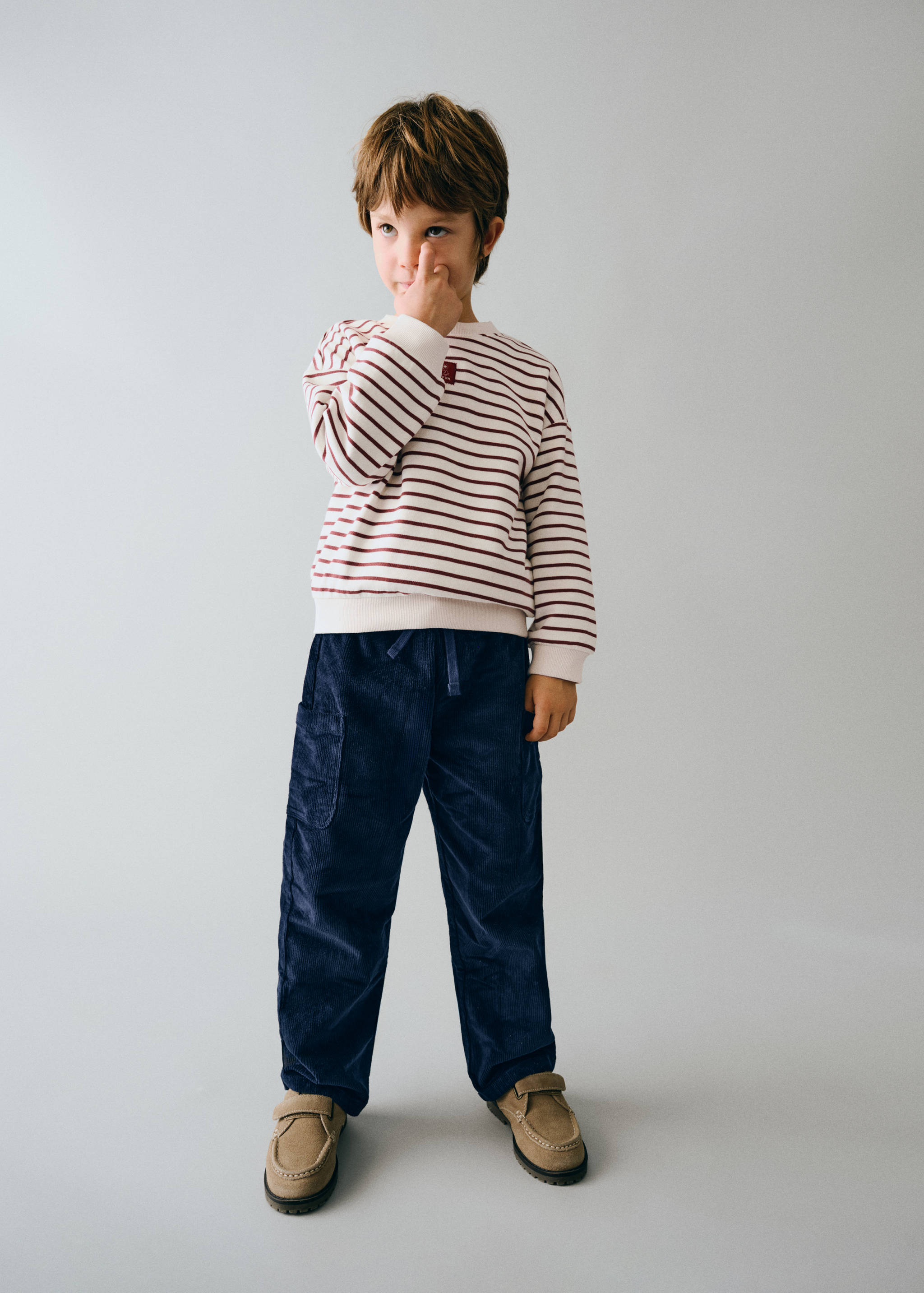 Cream and burgundy striped sweatshirt worn with dark blue corduroy trousers.