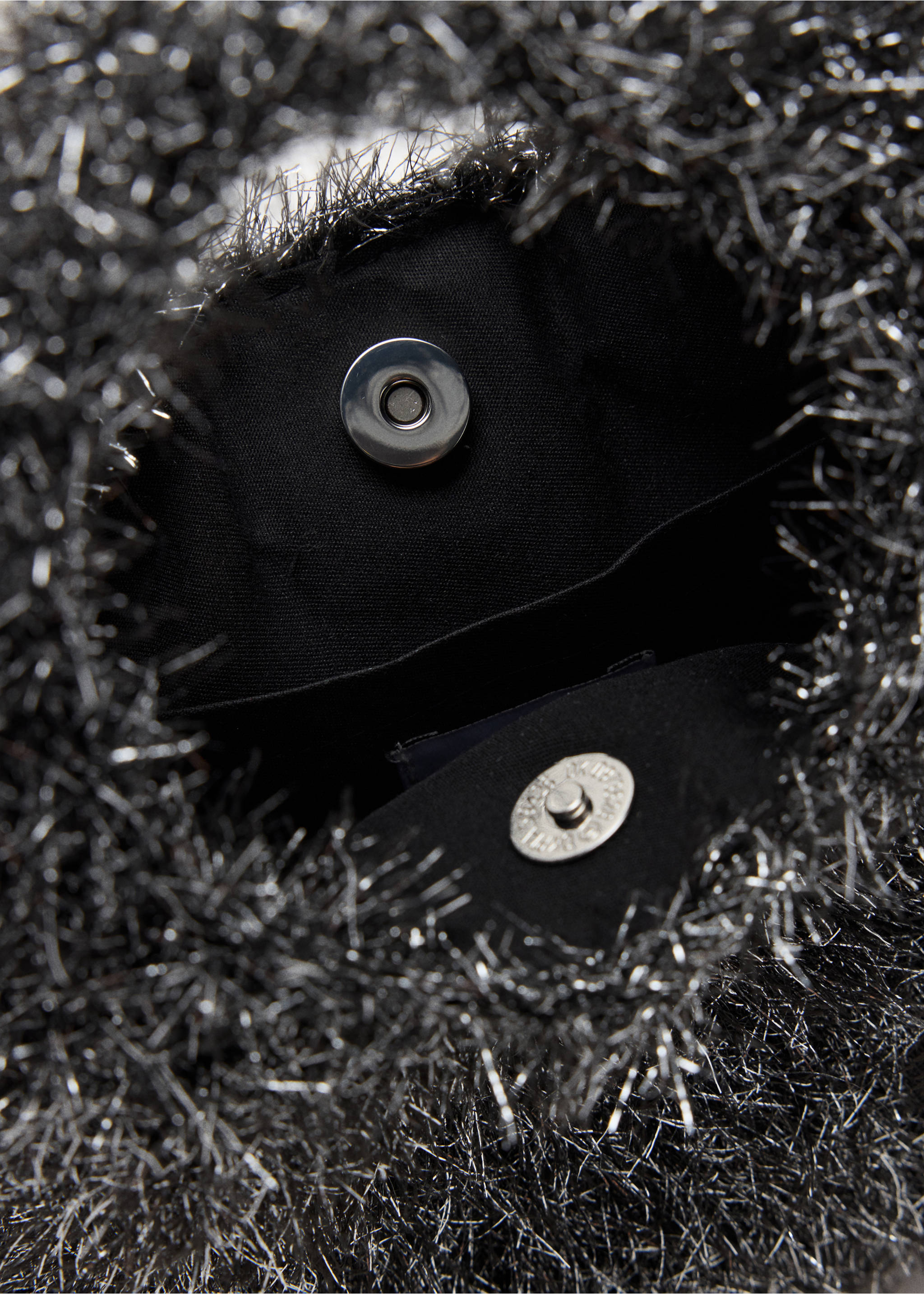 Primer plano de un minibolso texturizado en negro y plateado con cierre de broche magnético., Plata. Ref: 37078282-00.