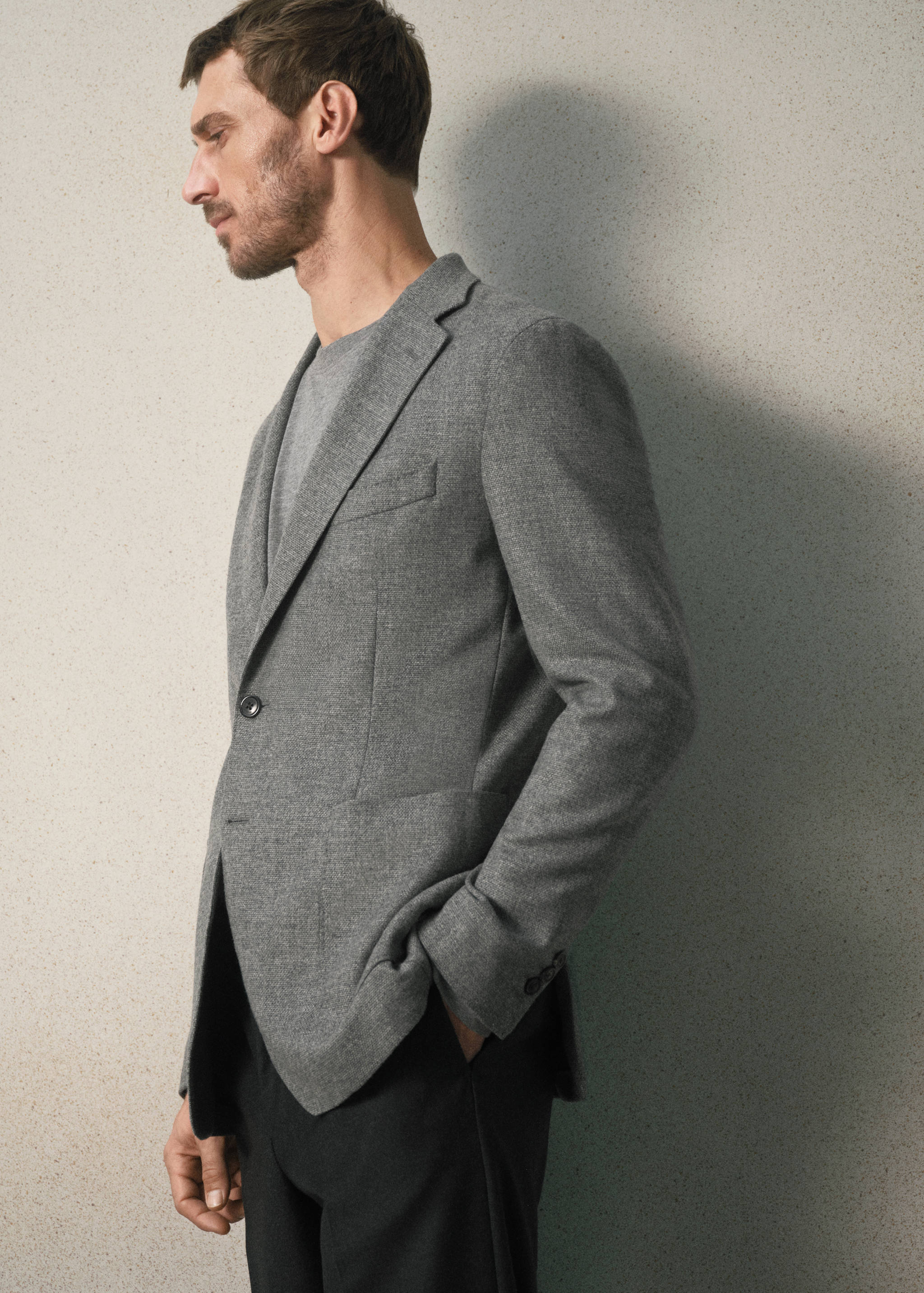 Grey single-breasted blazer with notched lapels worn over a t-shirt.