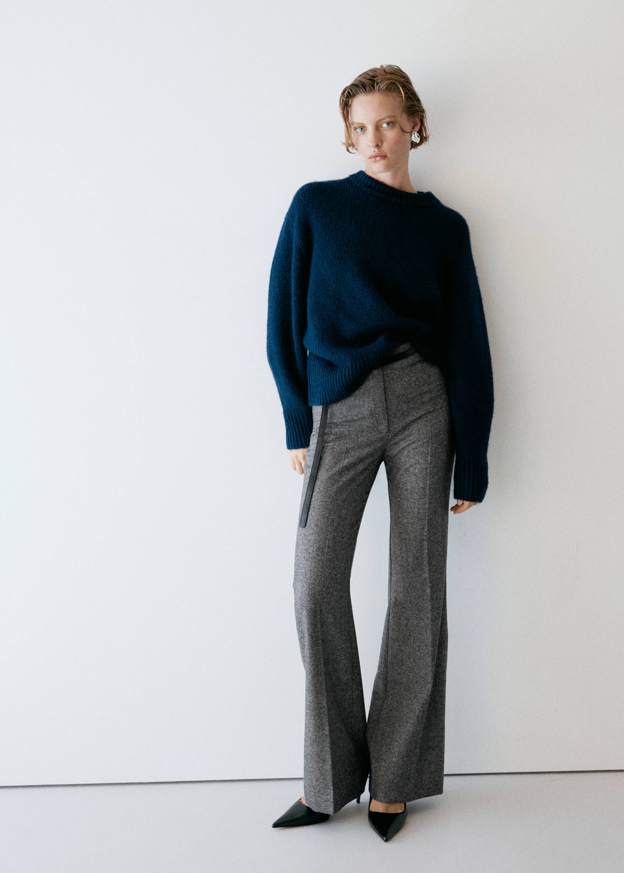 Grey patterned wide-leg trousers worn with a dark blue sweater.