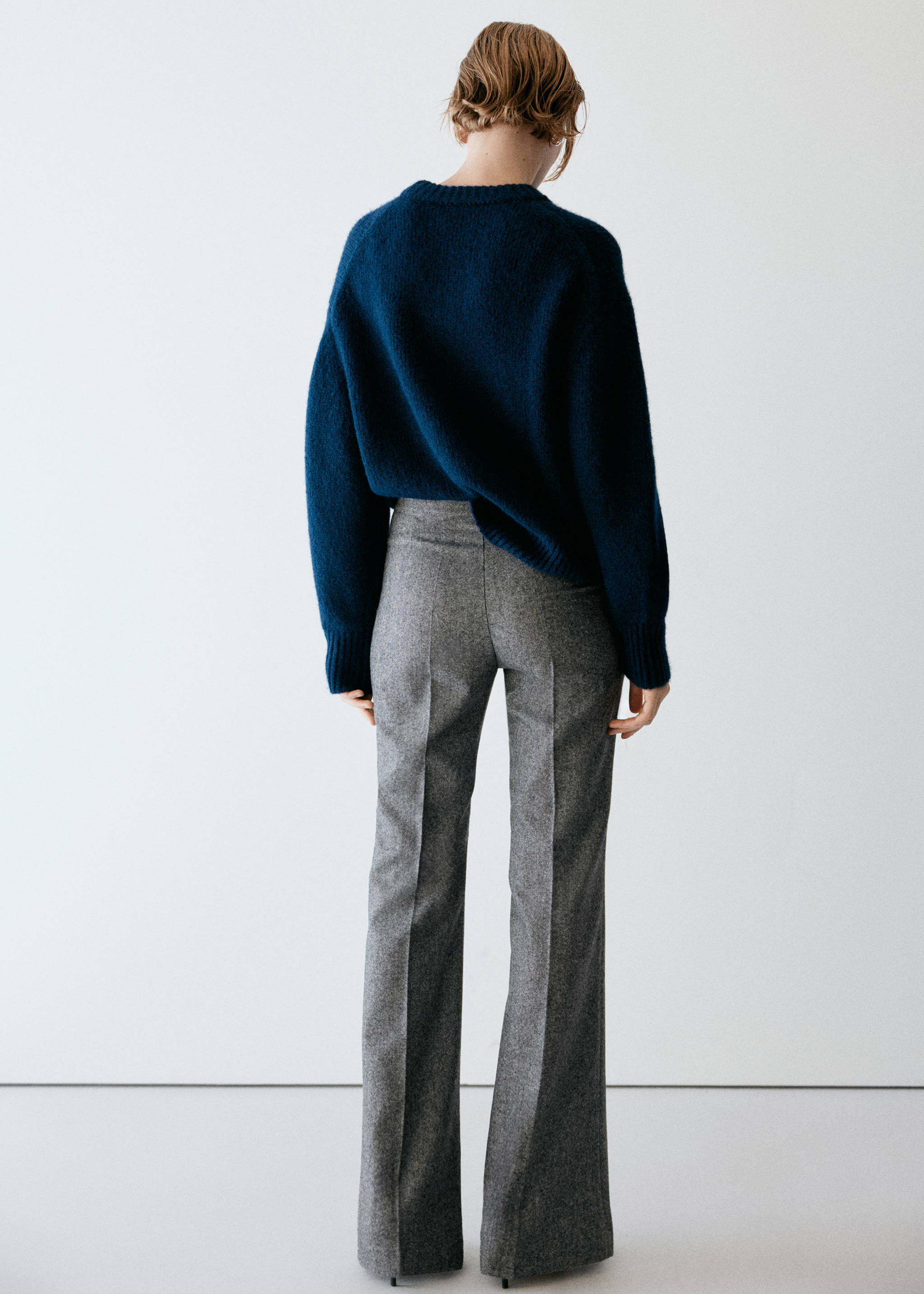 Grey patterned trousers from the back, worn with a dark blue sweater.