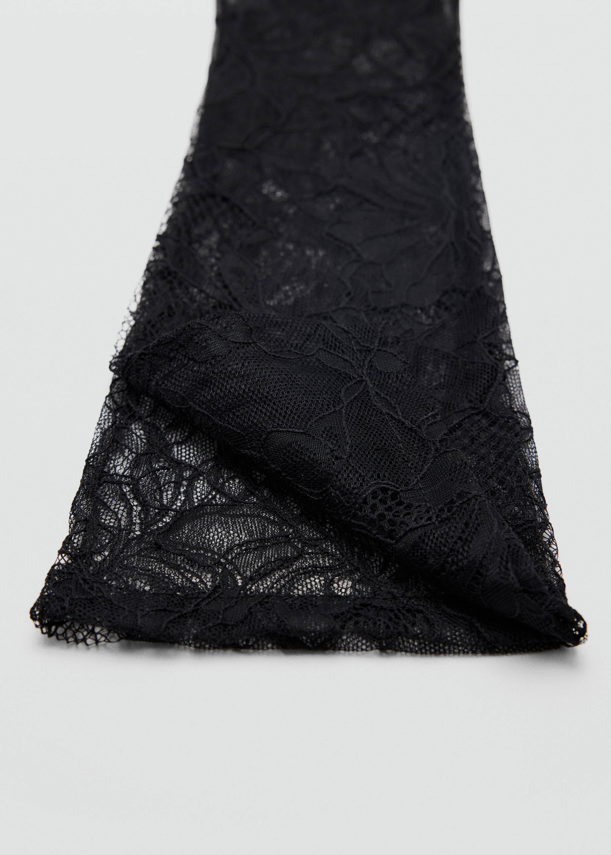 Close-up of black lace gloves featuring intricate floral patterns.