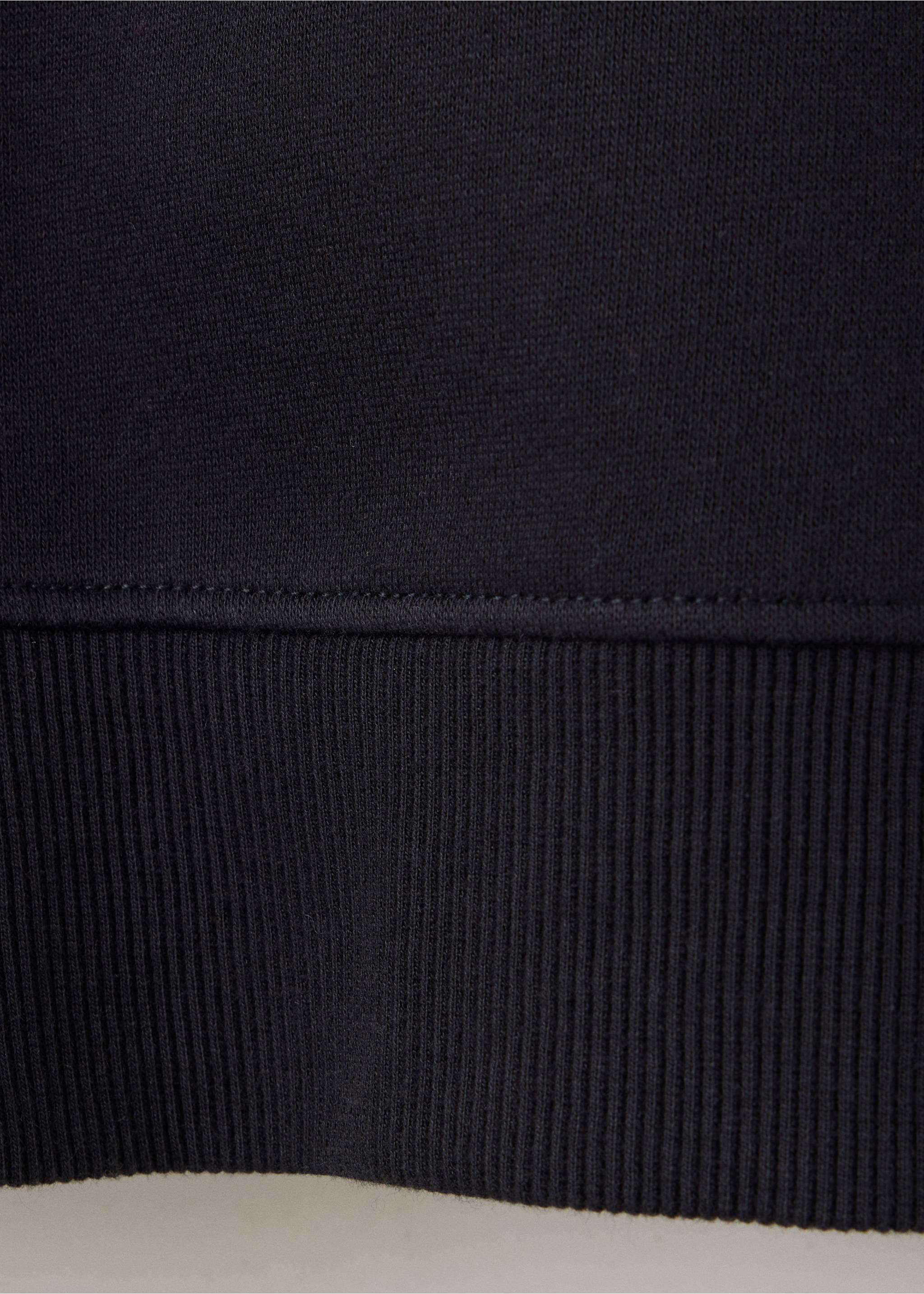 Close-up of the ribbed hem and fabric detail on a dark navy sweatshirt., Black. Ref: 37078636-00.