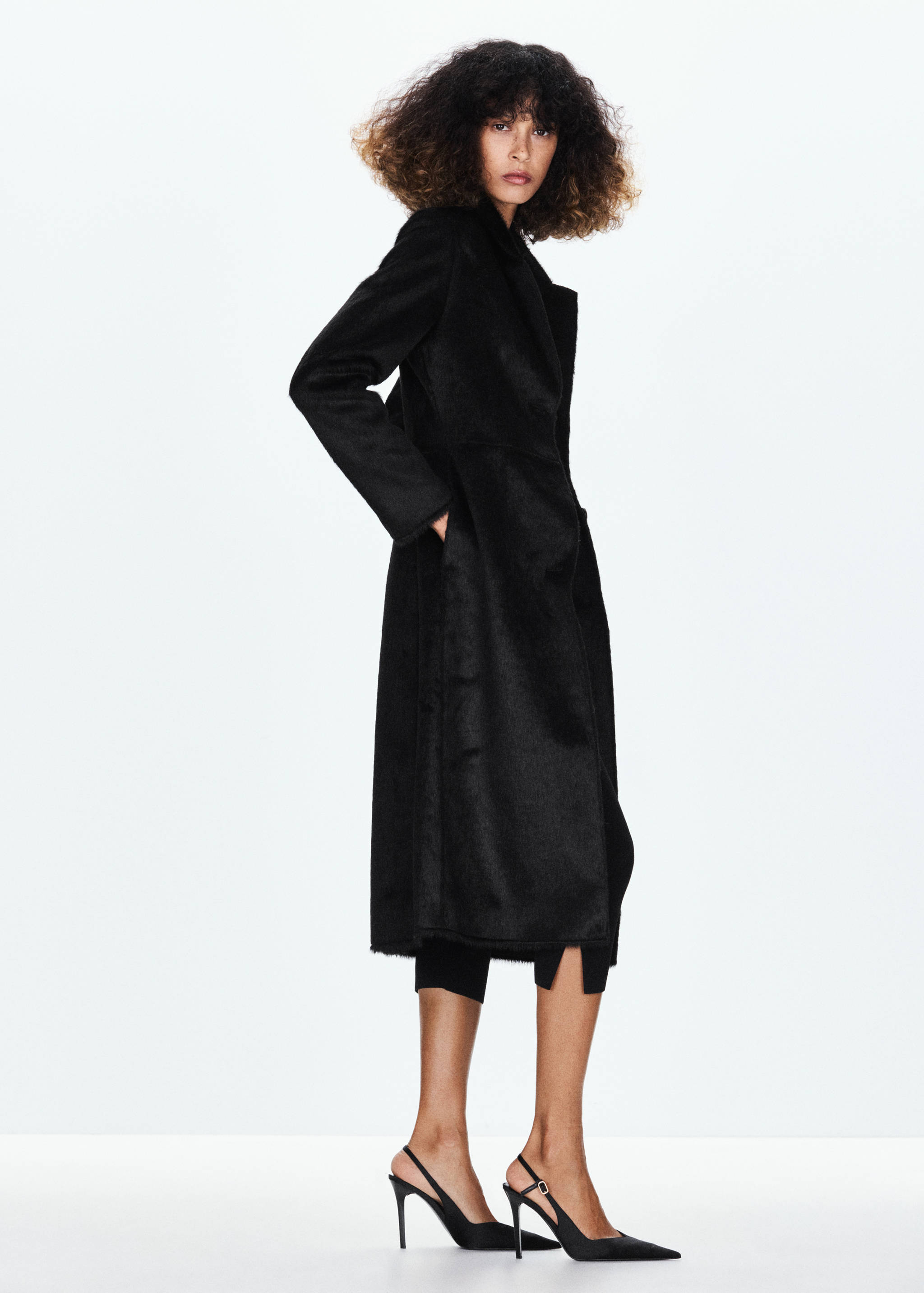 Long black coat with lapels and raw hem, worn by a model.