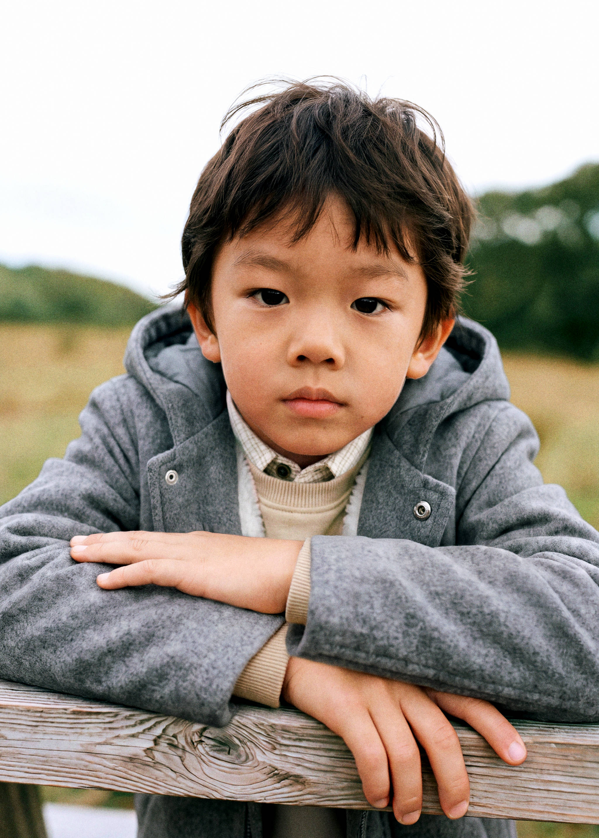 Grey hooded coat for kids with snap button details at the collar.