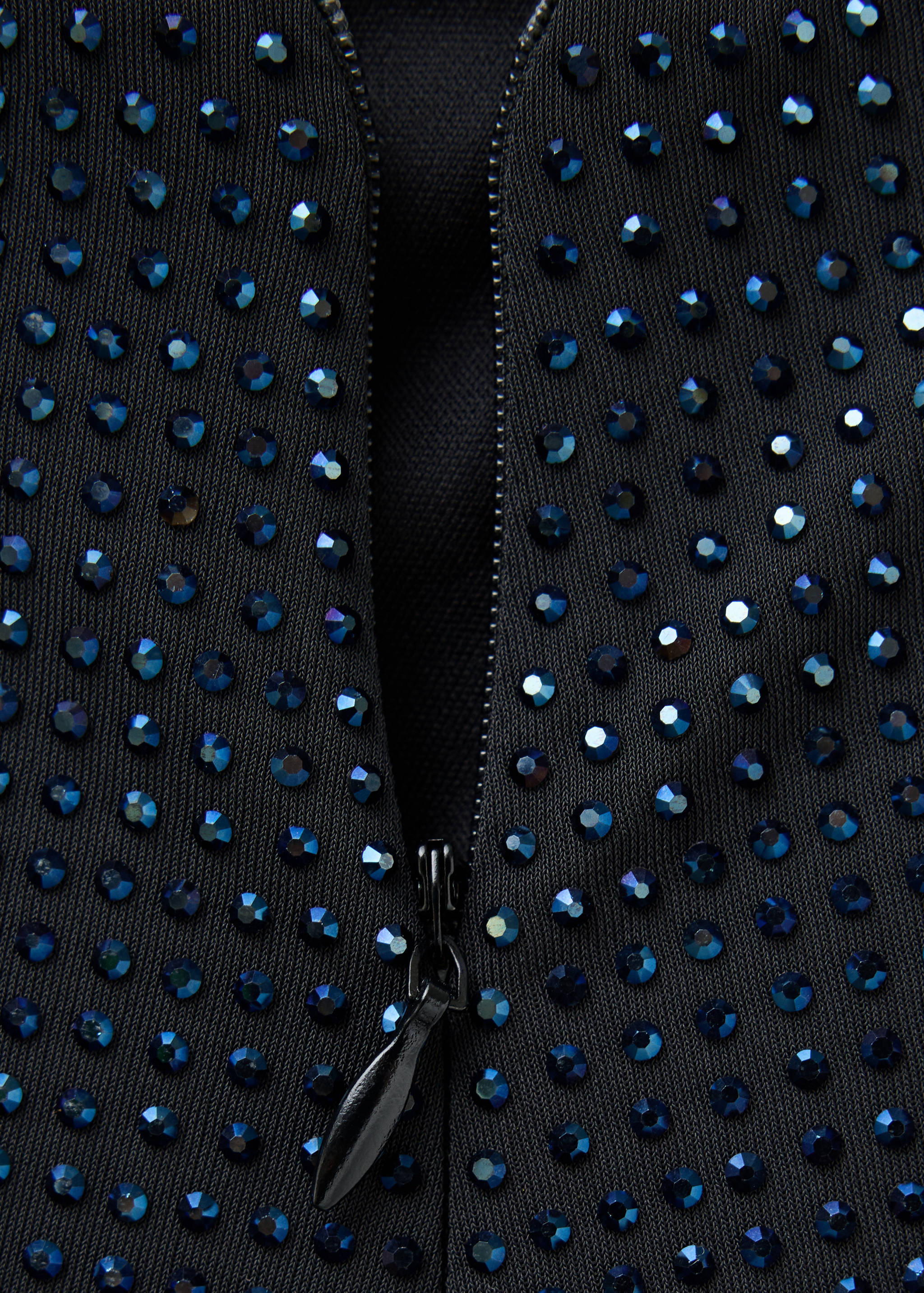 Close-up of a black skirt with blue rhinestone embellishments and a zip.