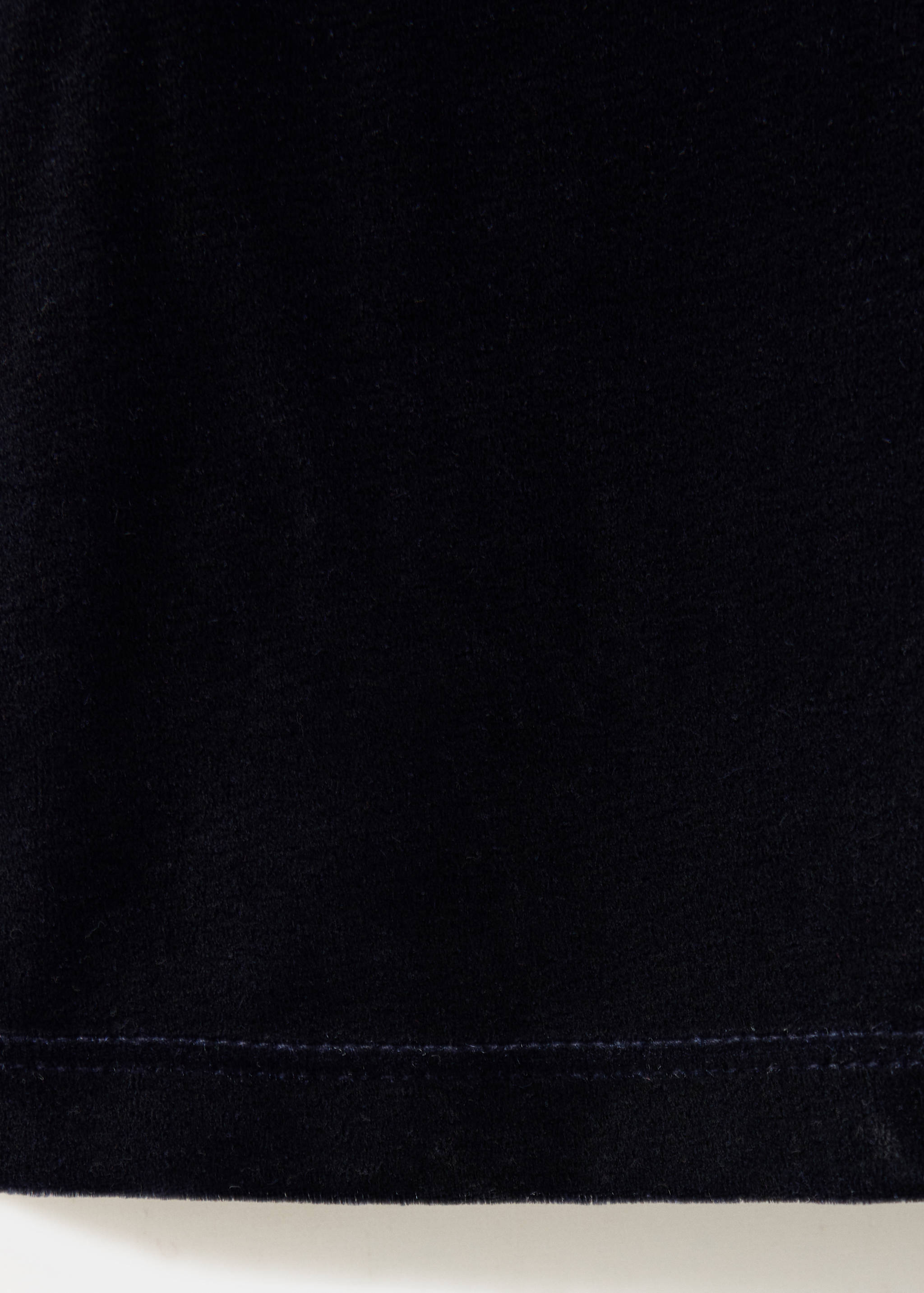 Detalle de tejido de los pantalones azul oscuro que muestra la suave textura de terciopelo.