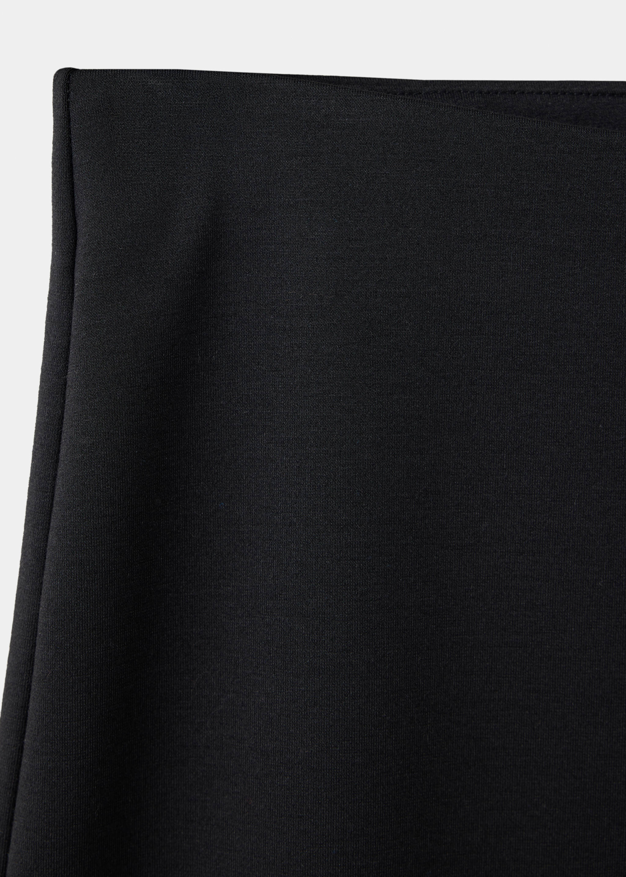 Close-up of the waistband on black trousers.