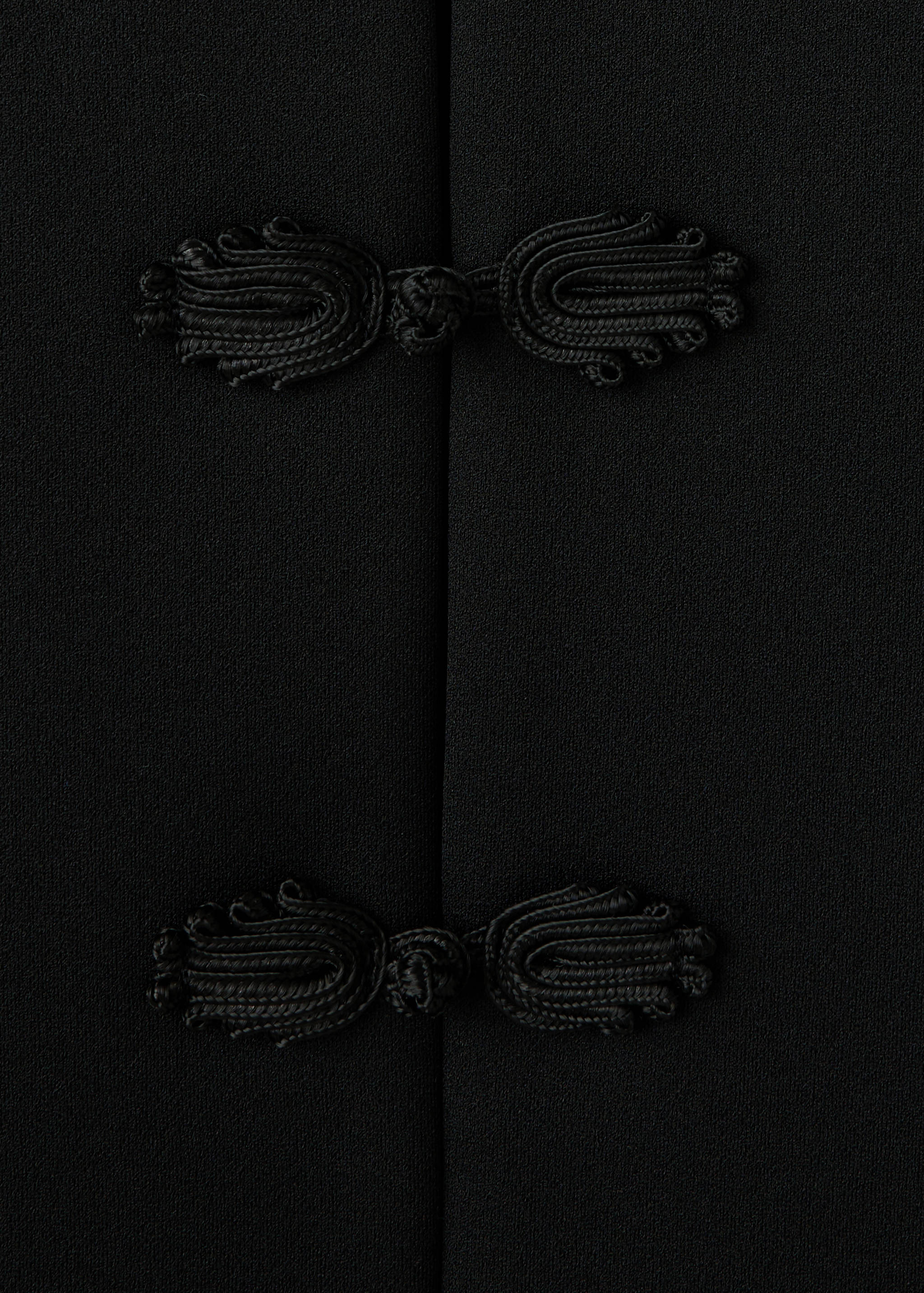 Black jacket detail showing black knotted cord frog closures.