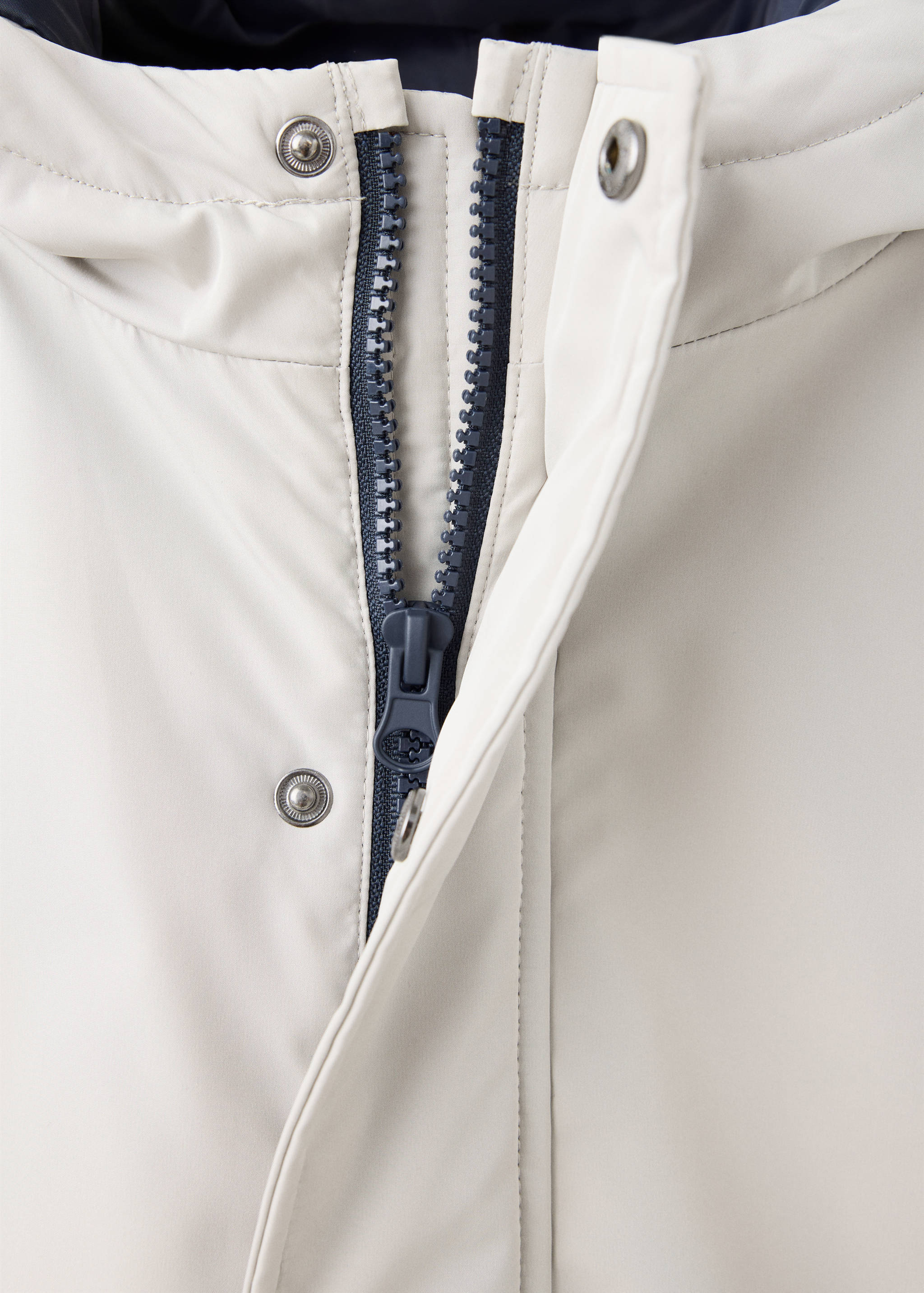 Close-up of a cream anorak with a contrasting navy zip and press-stud flap.
