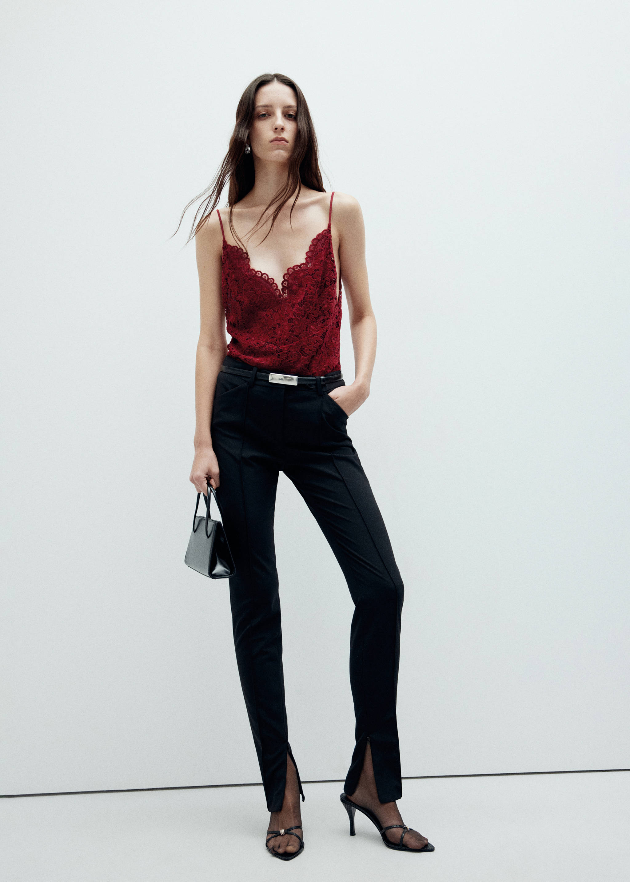 Burgundy lace camisole top with spaghetti straps and a scalloped V-neckline, styled with black trousers.