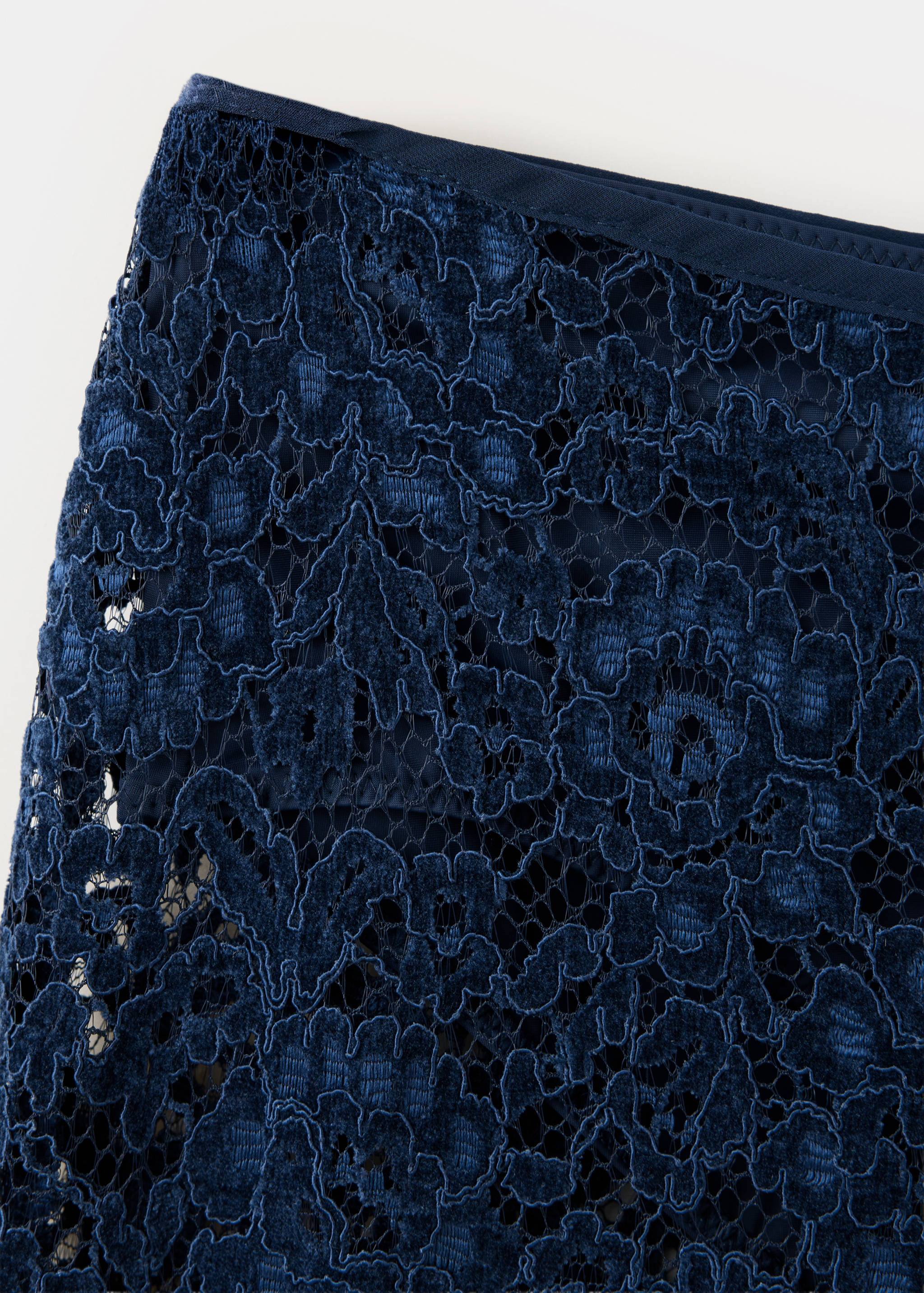 Close-up of dark blue lace trousers detail.