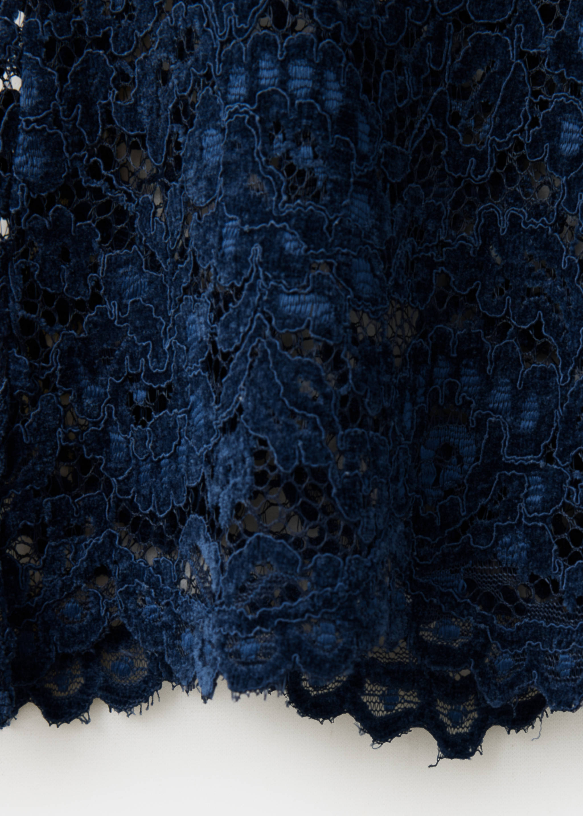 Close-up of navy blue lace trousers showing fabric texture.