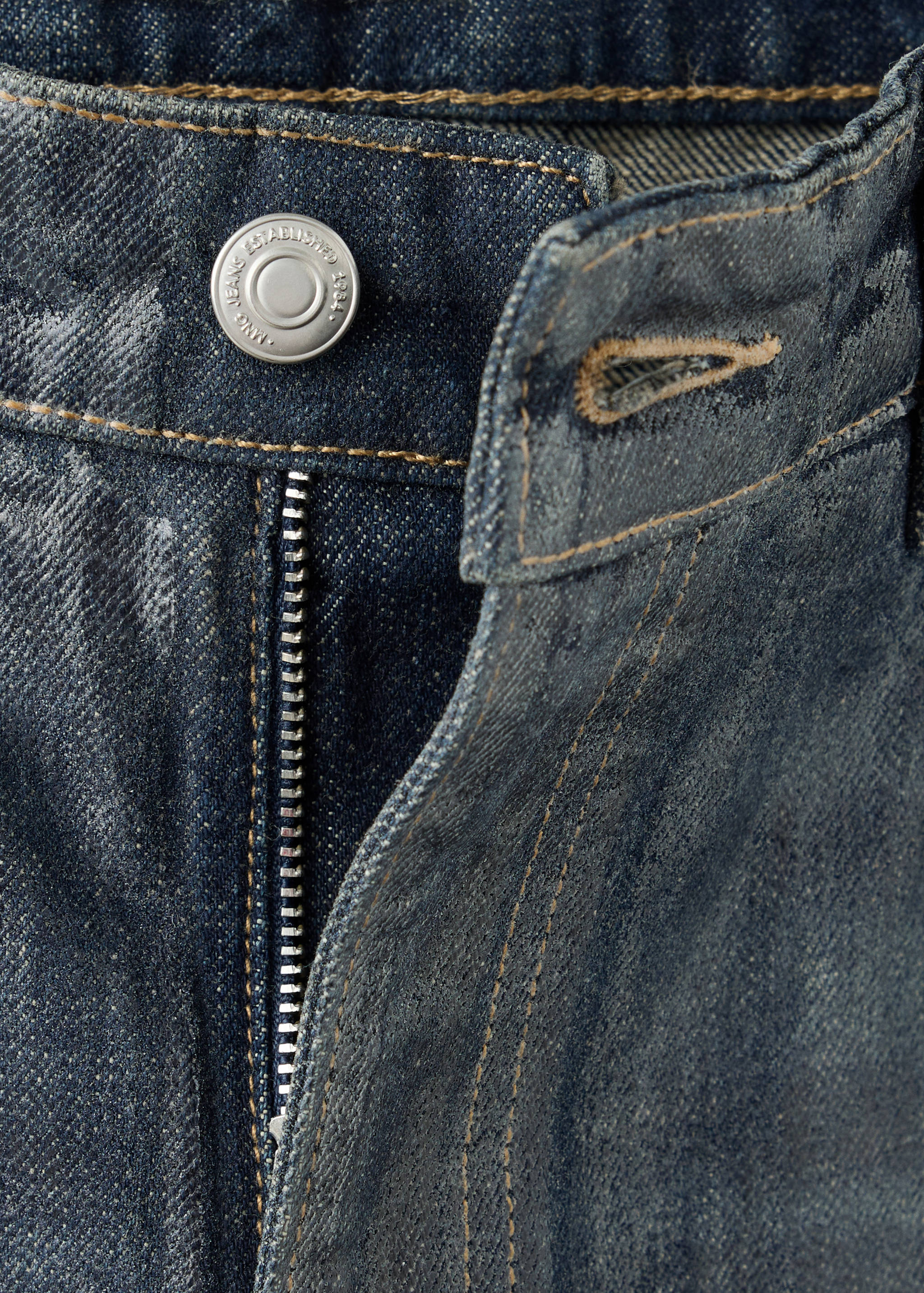 Close-up of blue denim trousers showing the waistband, button, and zipper.