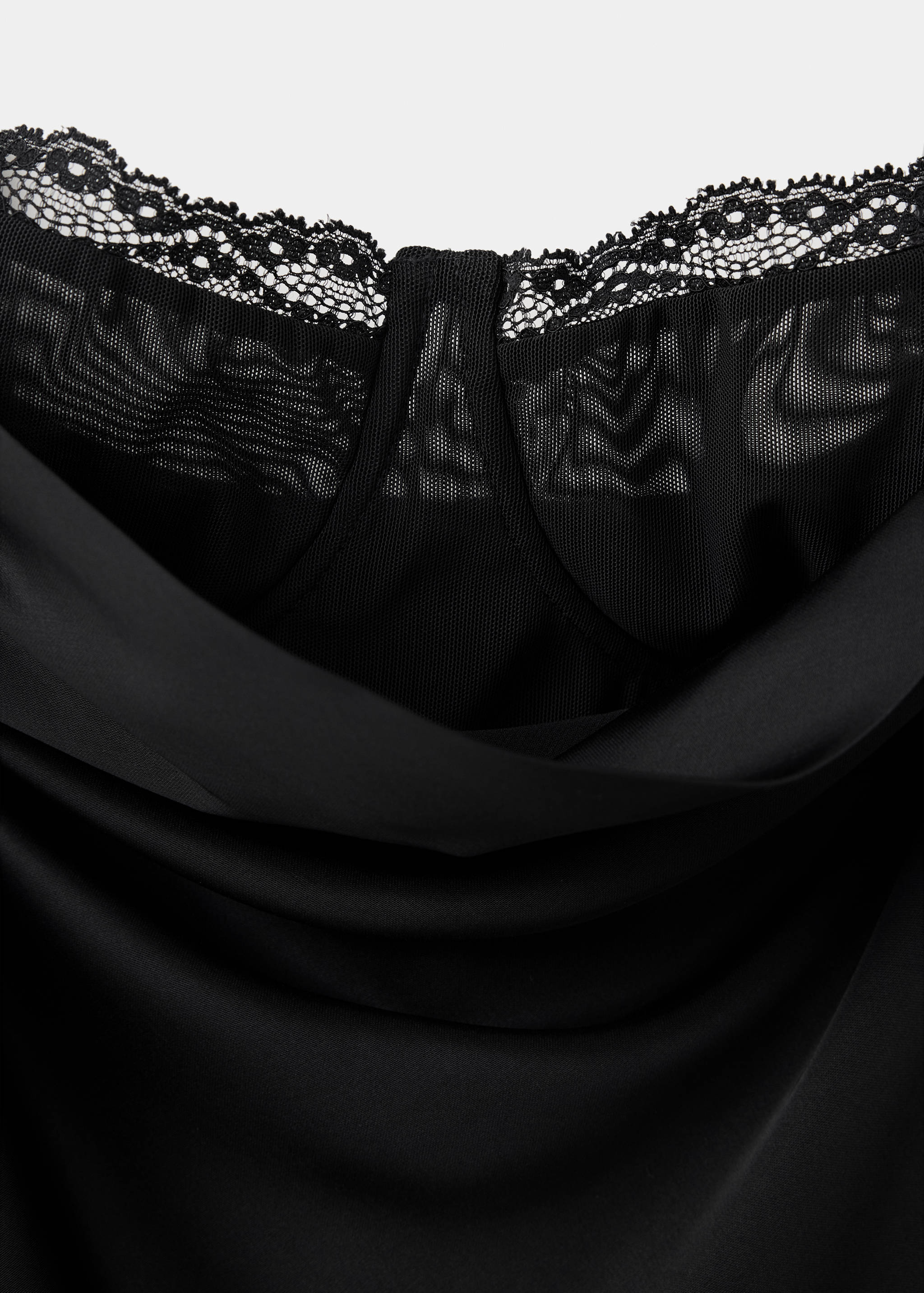 Close-up of a black dress with a cowl neck, sheer mesh insert, and lace trim.