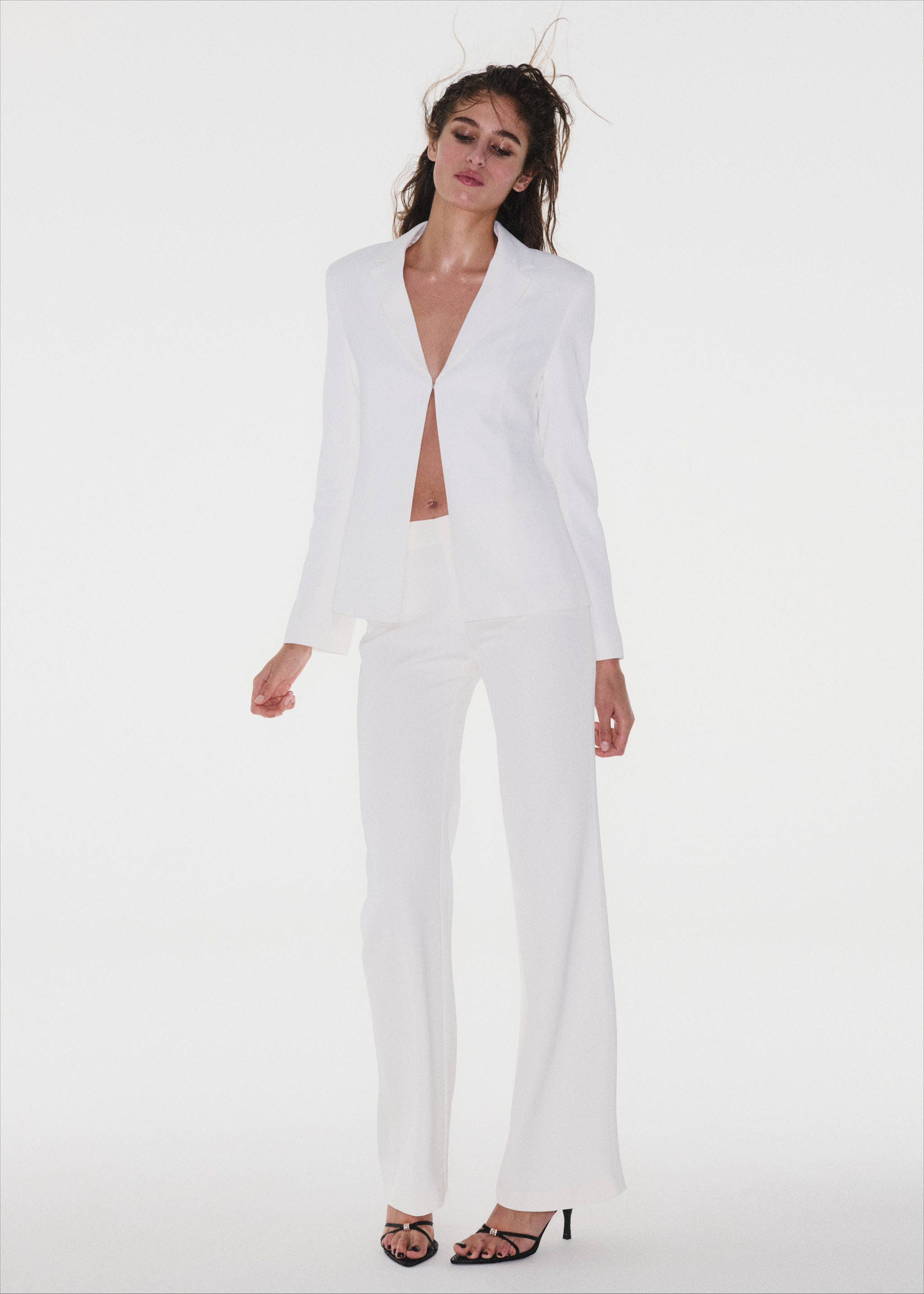 White tailored blazer with peaked lapels and a single-button fastening, worn with matching trousers.