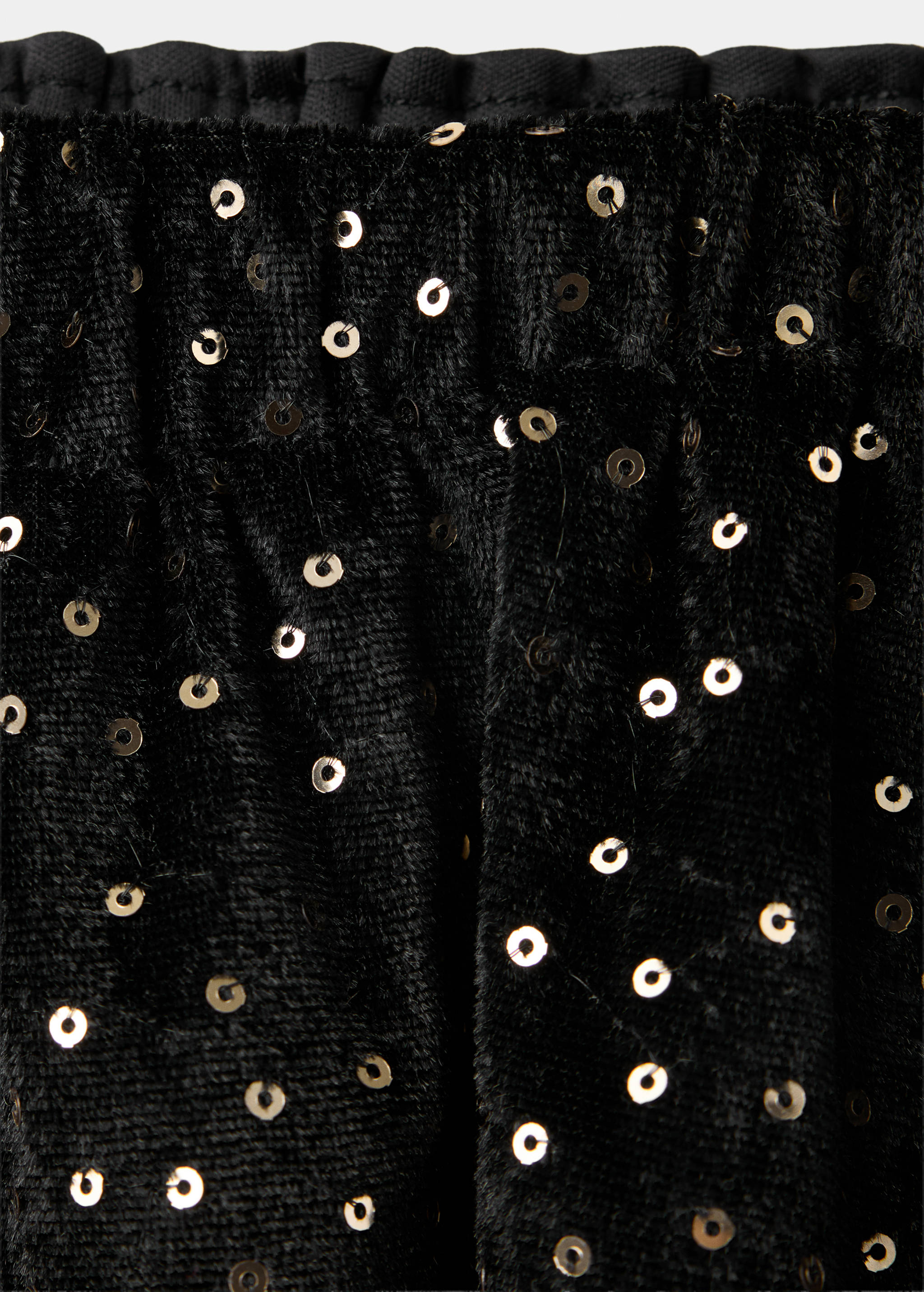 Close-up of a black velvet skirt with silver sequins and elastic waist.