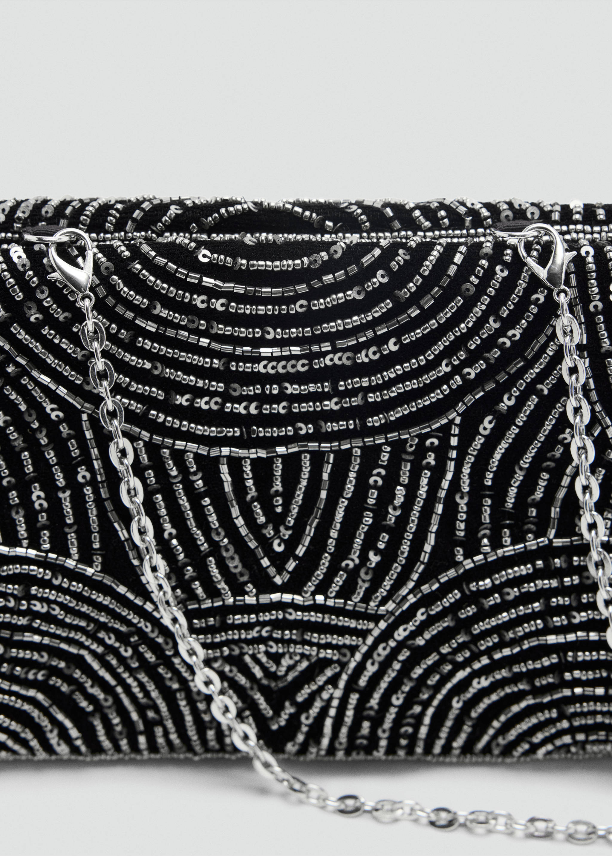 Close-up of a black beaded handbag with a silver metal chain strap., Black. Ref: 37079209-00.