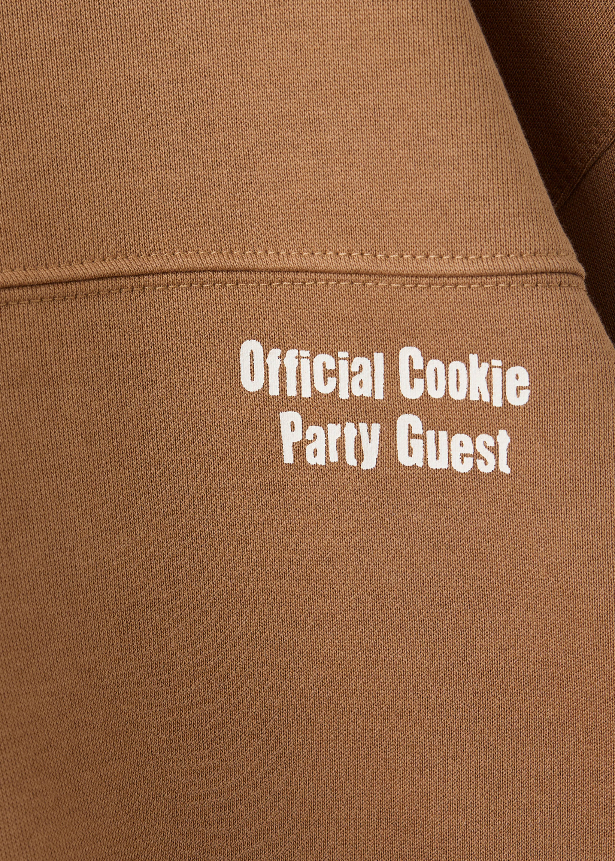 Brown sweatshirt close-up with white Official Cookie Party Guest text.