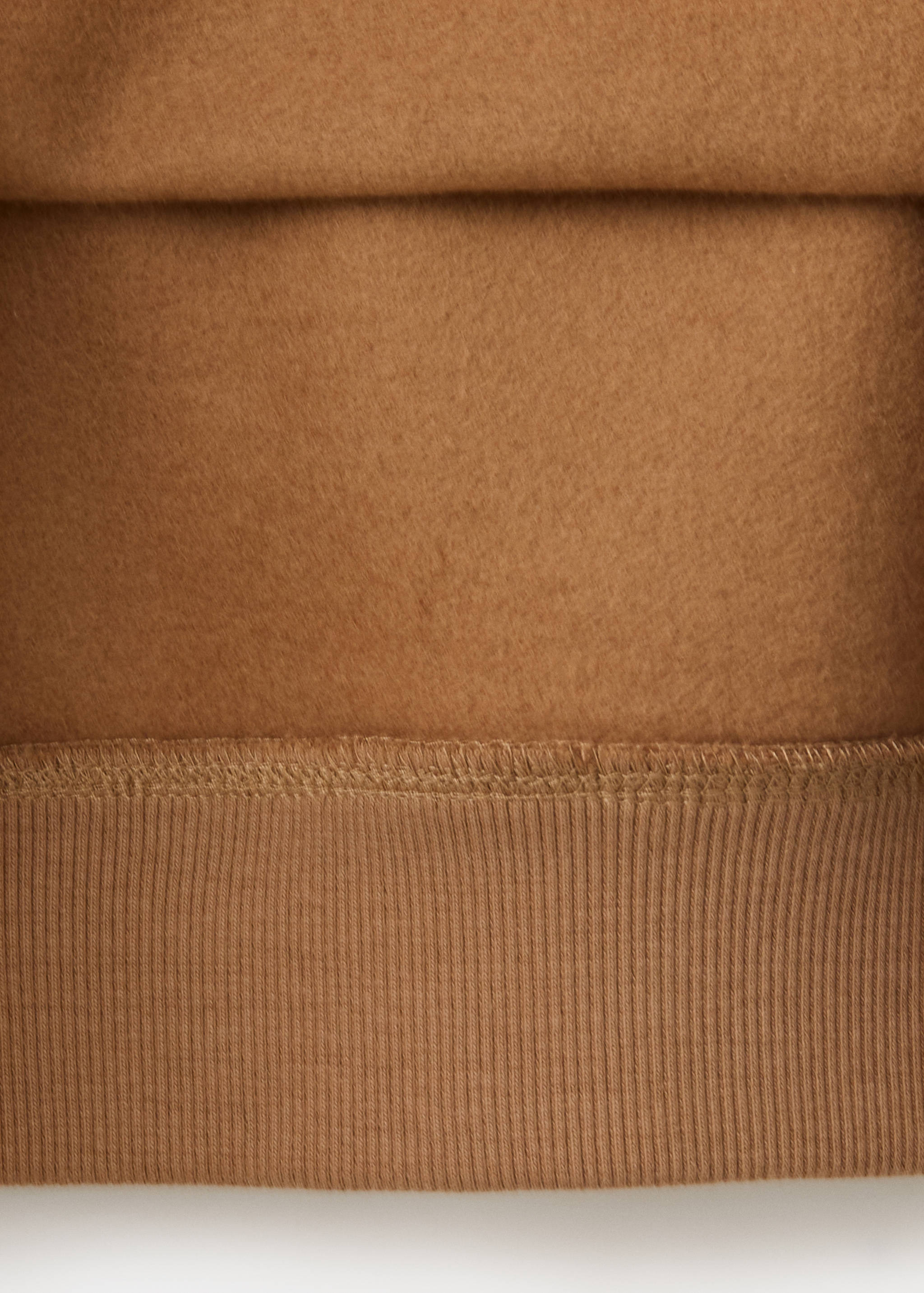 Brown sweatshirt fabric detail showing the soft texture and ribbed hem.