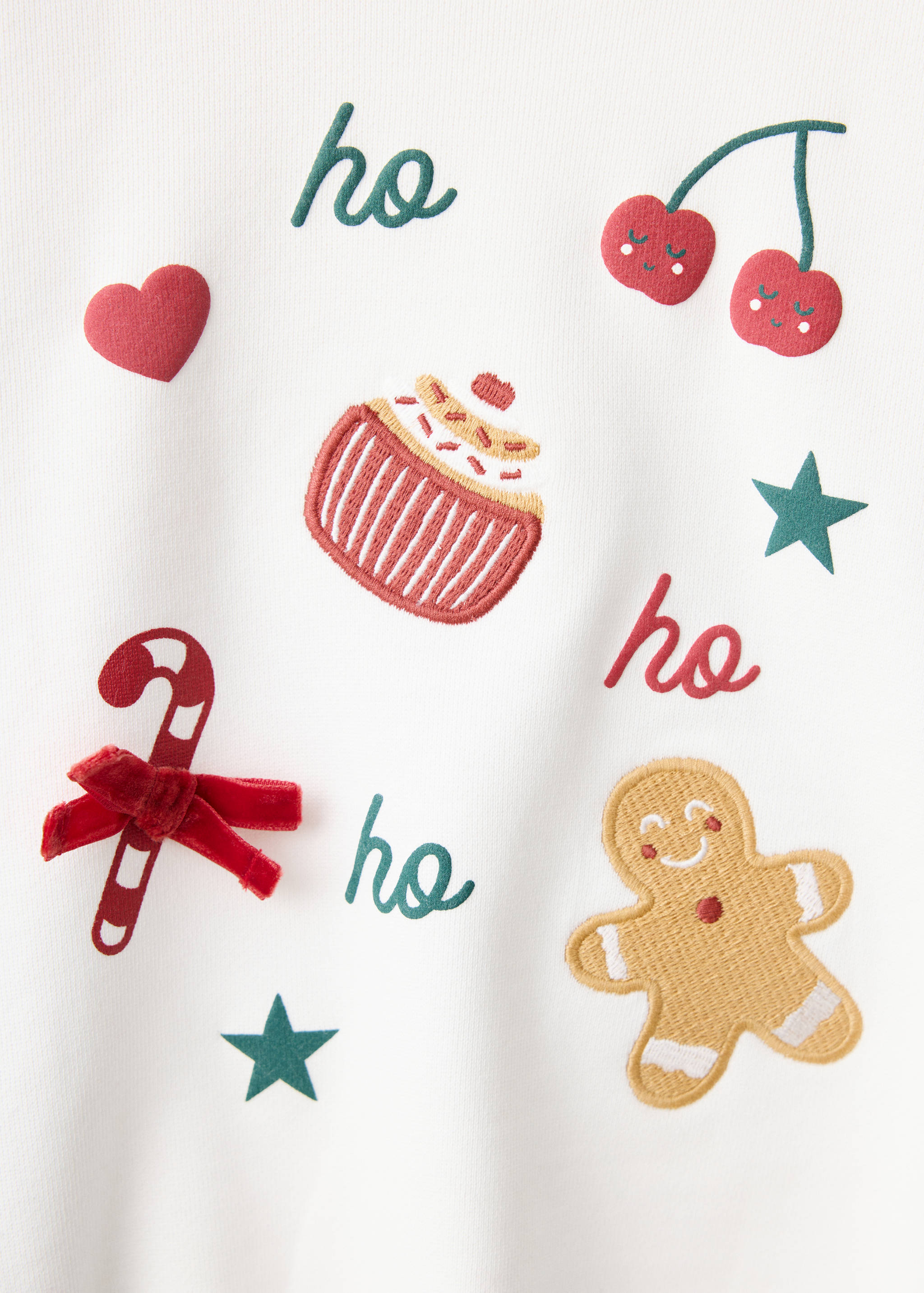 Detalle de sudadera blanca de niño con motivos navideños bordados y lazo.