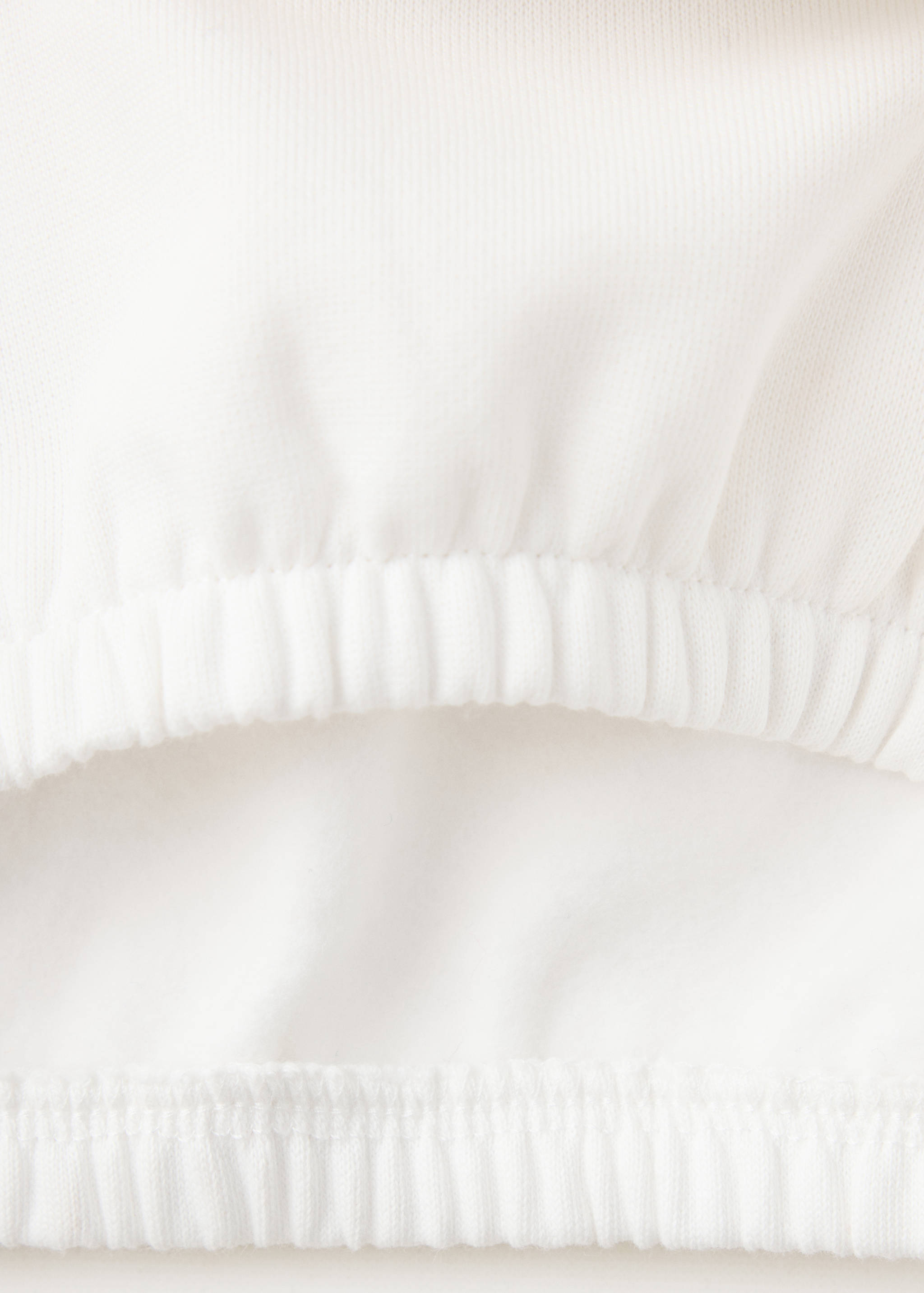 Primer plano del tejido y del bajo elástico en una sudadera blanca.
