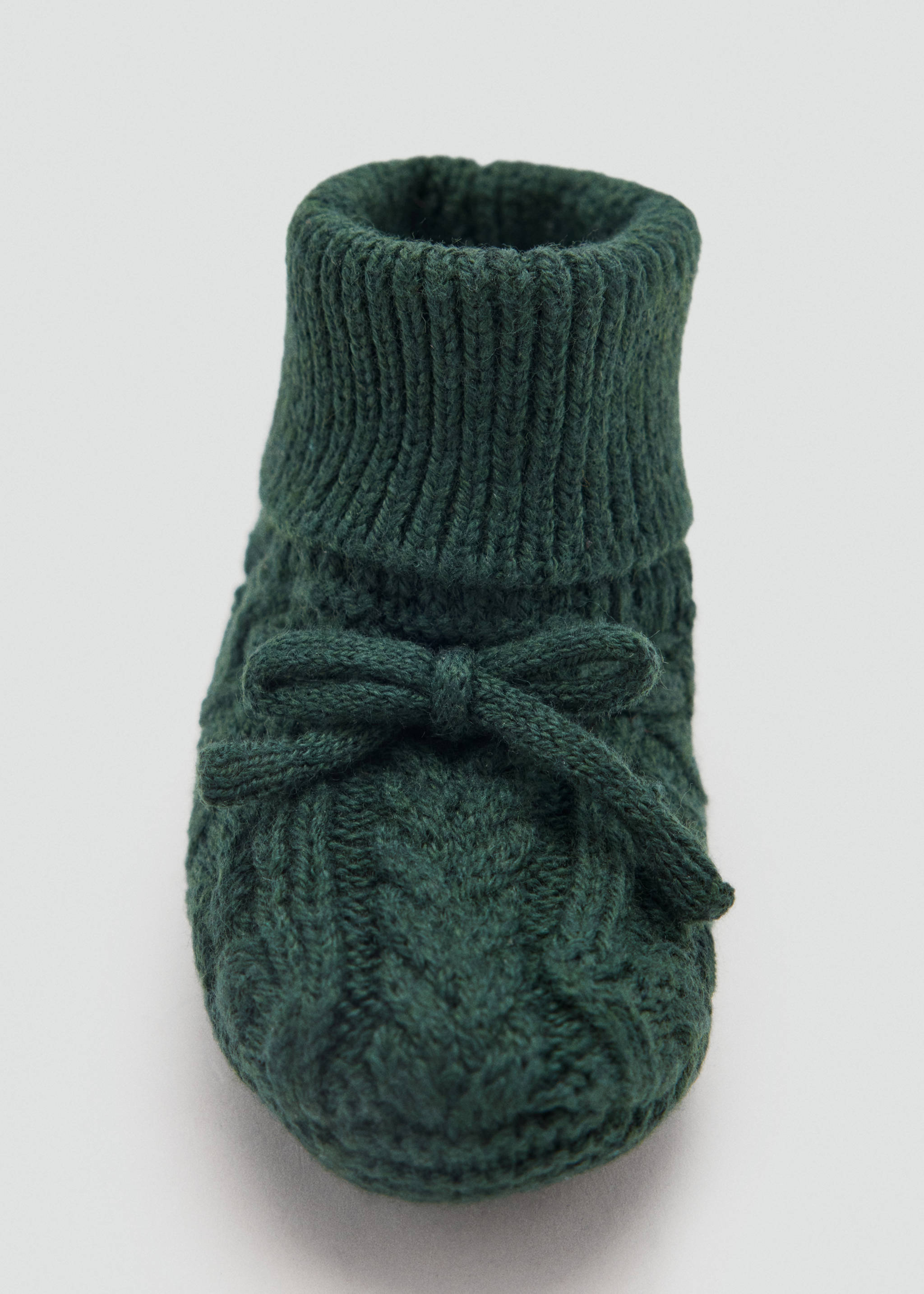 Dark green knitted kids' socks with a ribbed cuff and bow detail, shown in close-up.