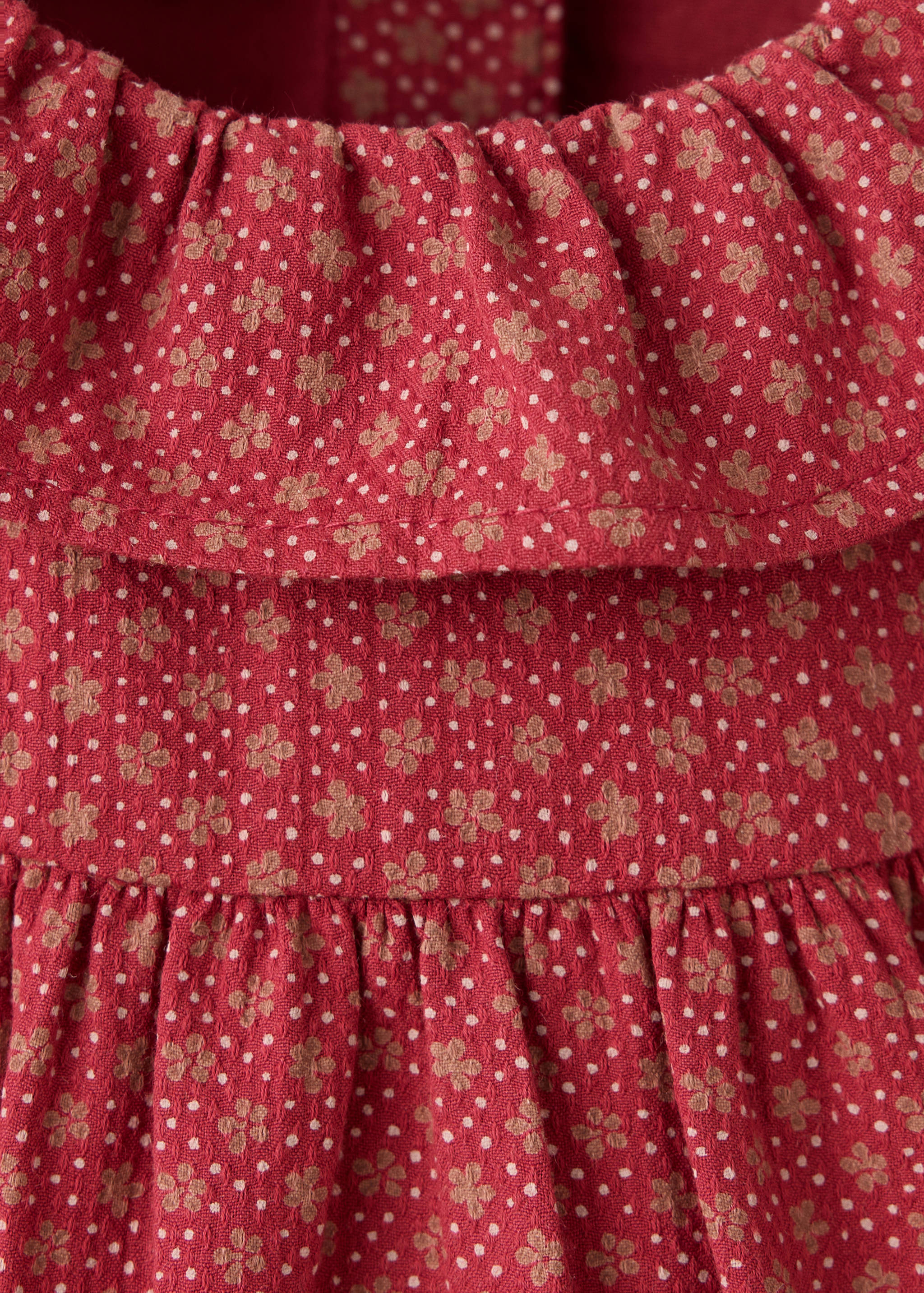 Red floral print baby romper detail with a ruffled collar.