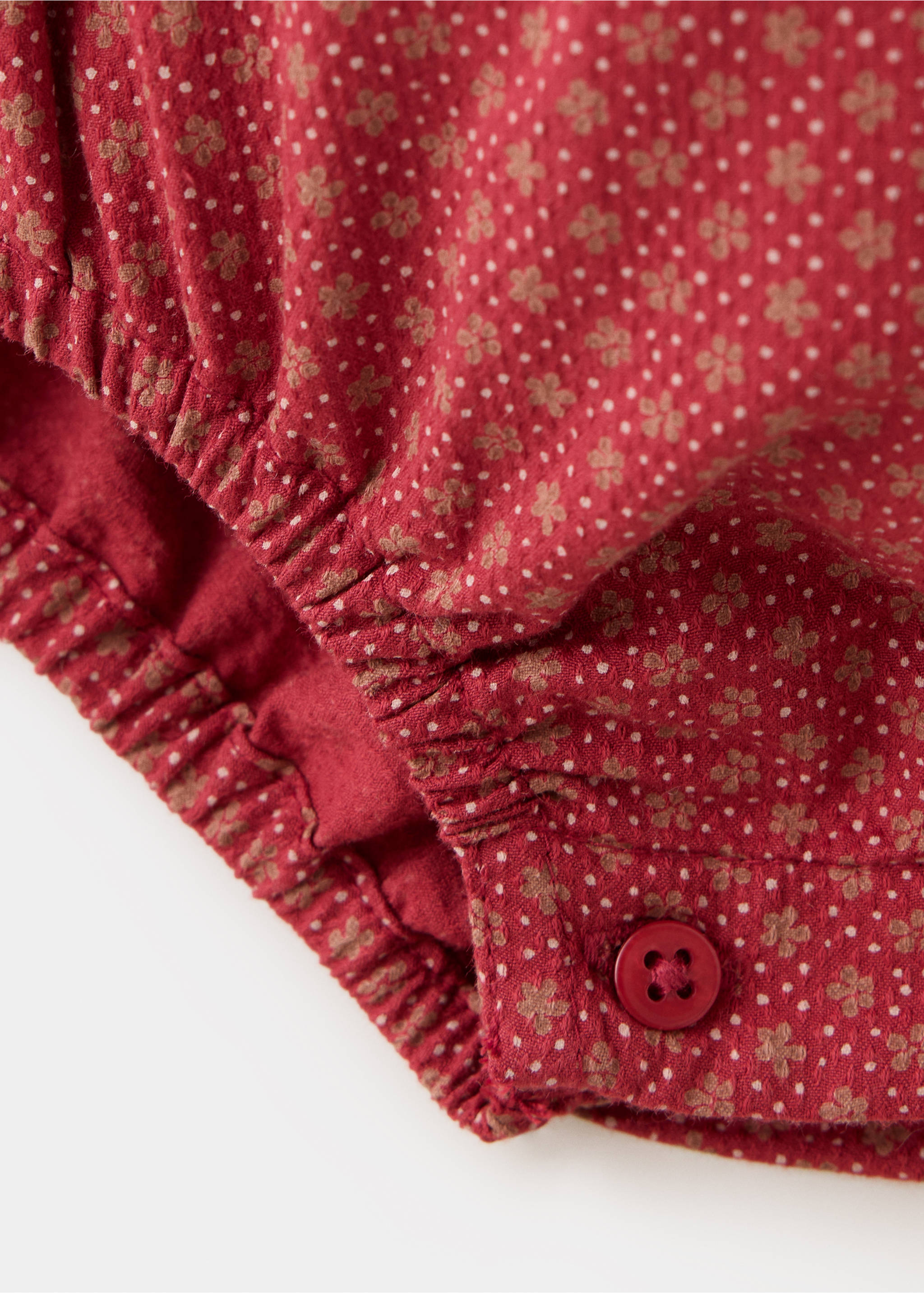 Close-up of red printed baby romper fabric with elasticated trim and button detail., Red. Ref: 37079218-00.