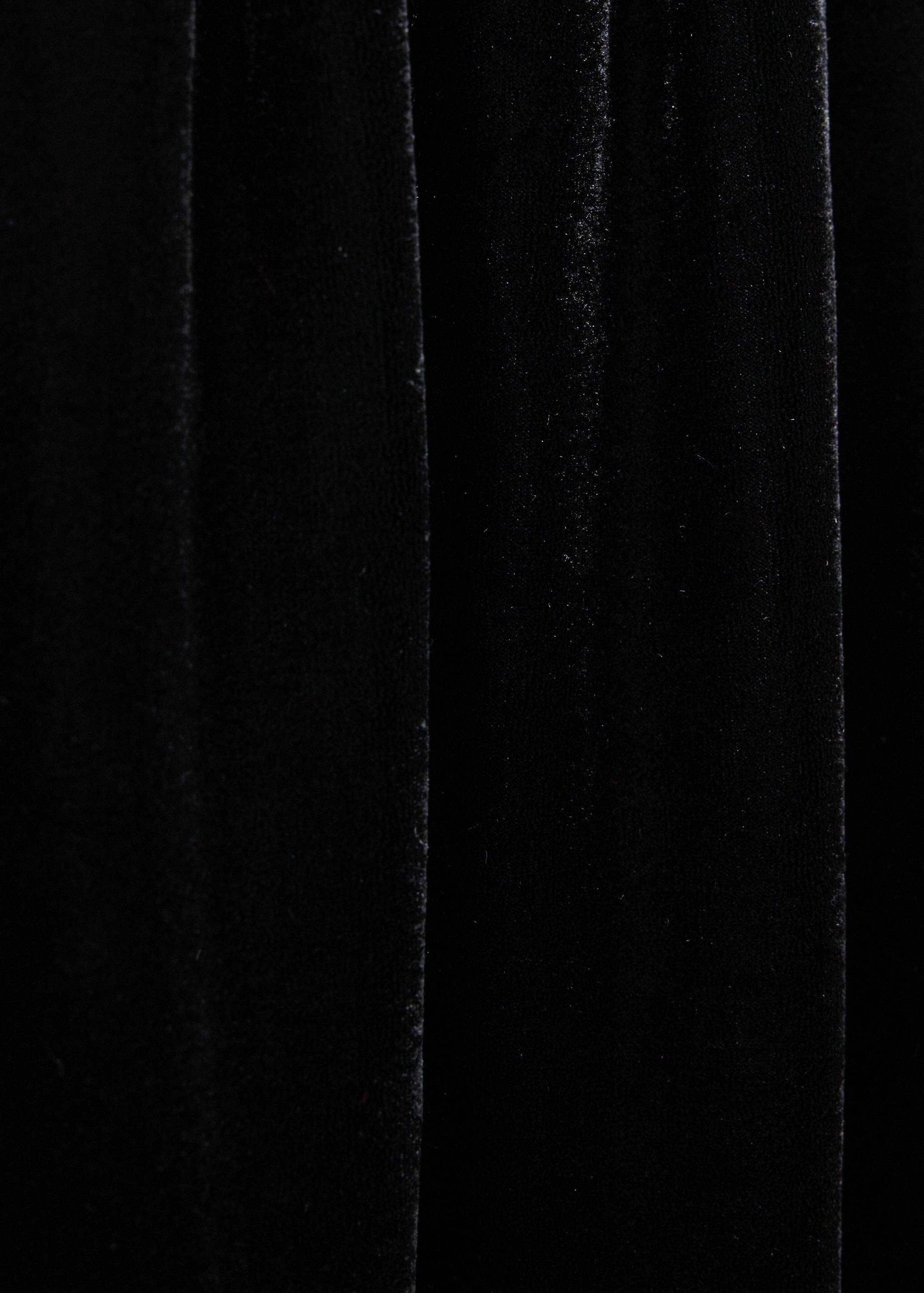 Close-up of black velvet fabric texture on trousers.