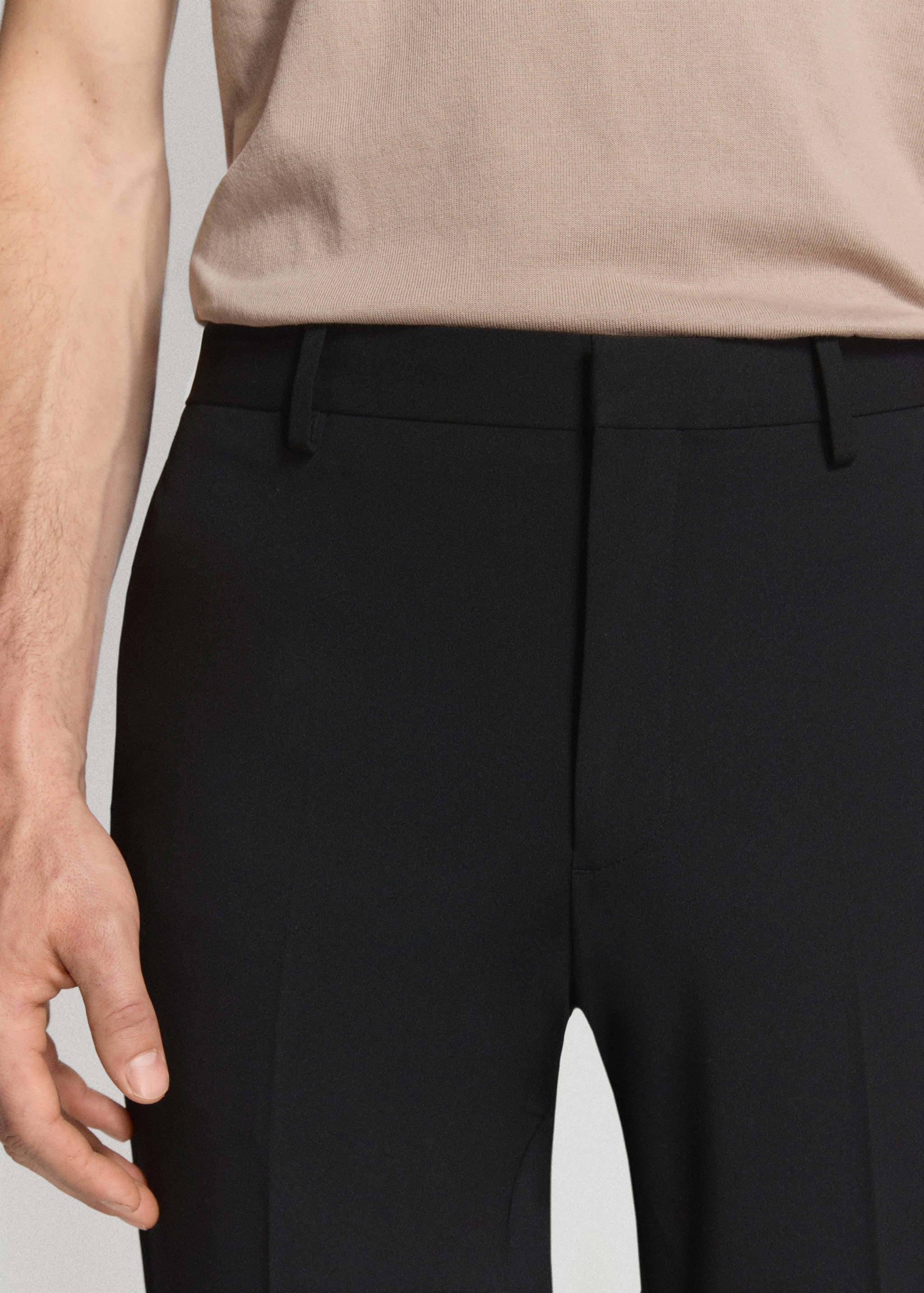 Close-up of black trousers with a structured waistband and belt loops.