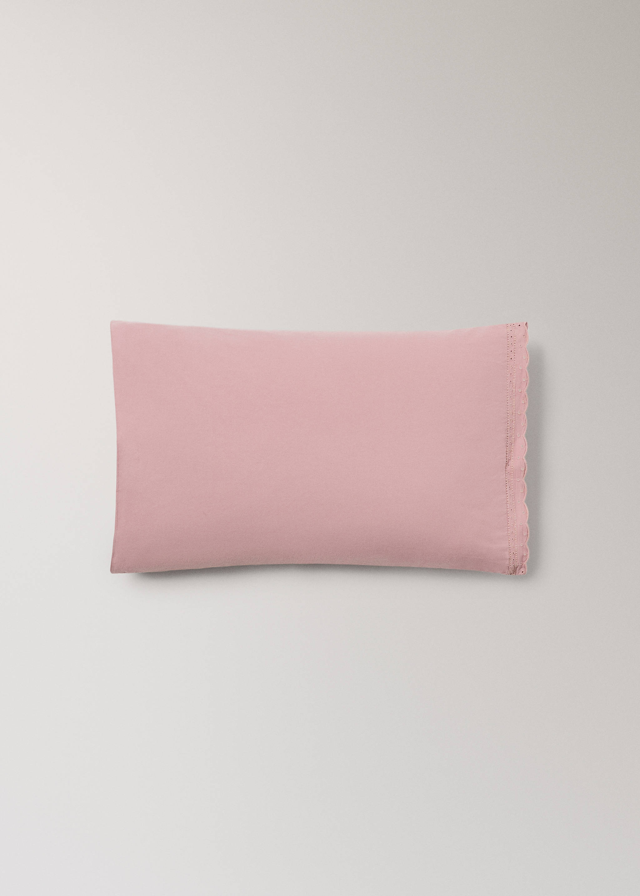 Pink cot pillowcase with a scalloped embroidered border.